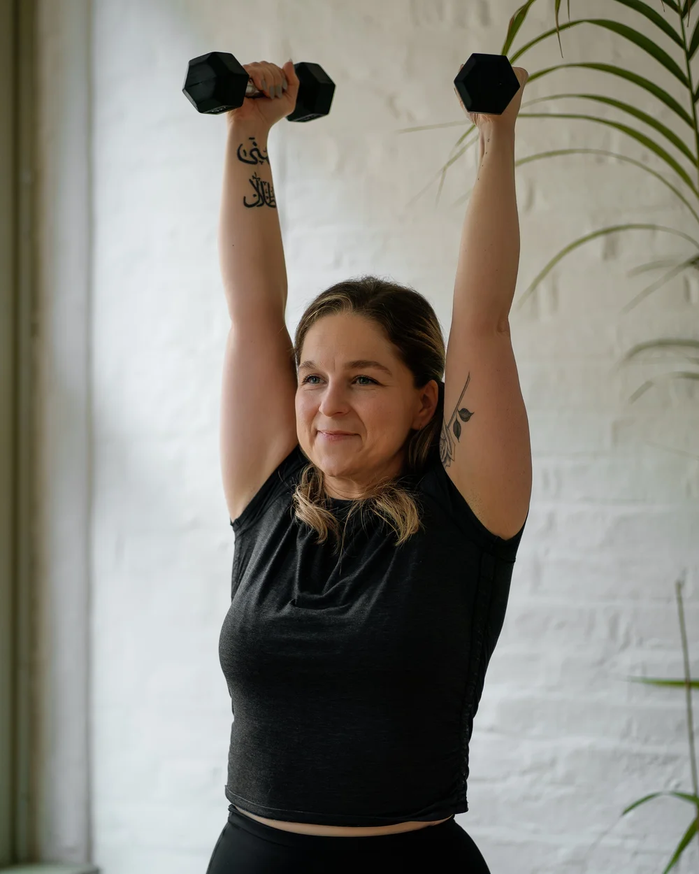 Karima lifting two dumbbells overhead