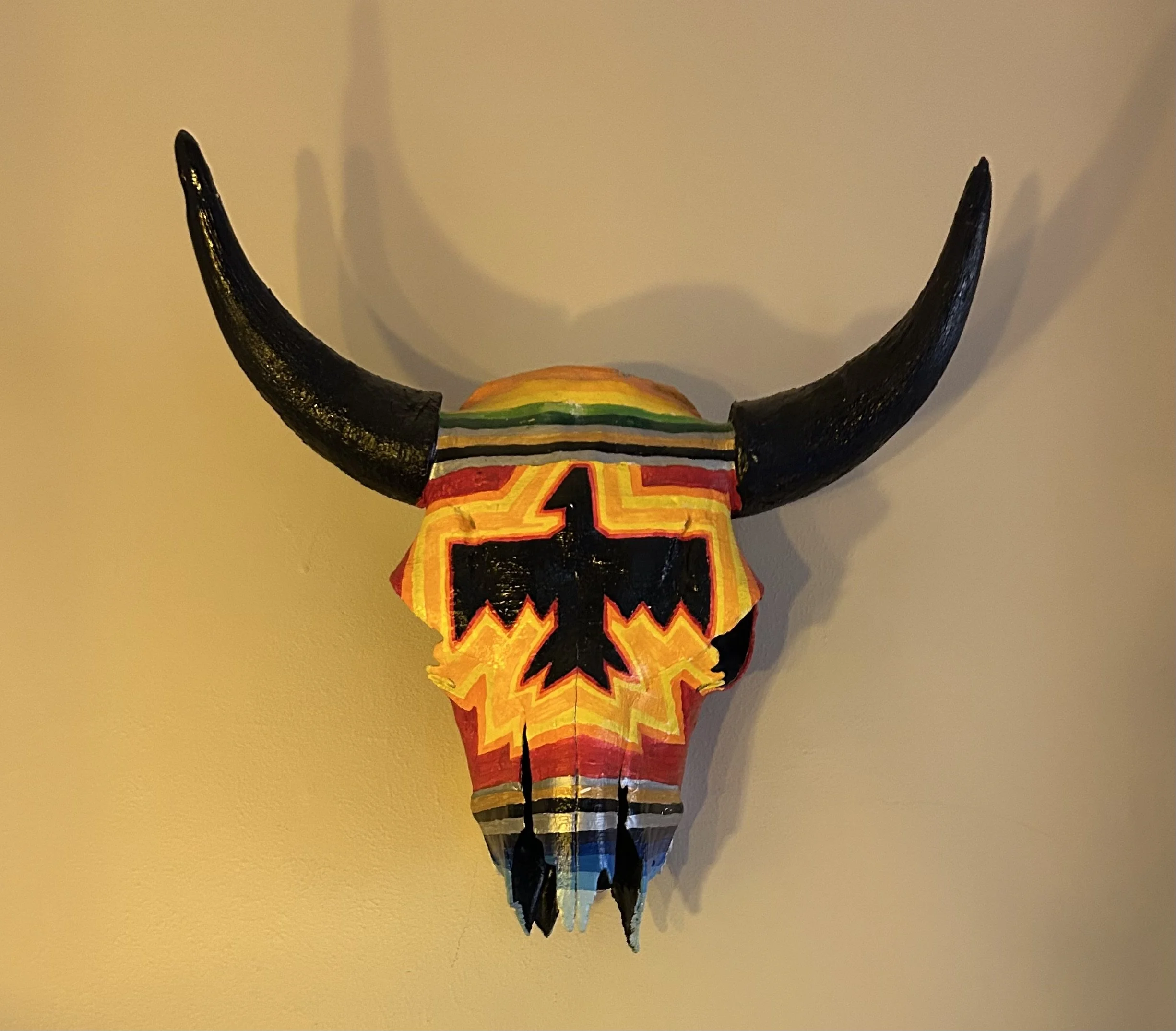 Colorful decorative skull with large black horns and geometric patterns.