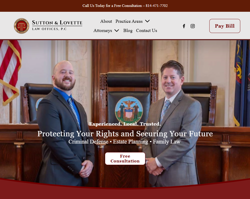 Two male lawyers in suits standing inside a courtroom, smiling at the camera with a judge's bench and an emblem in the background.