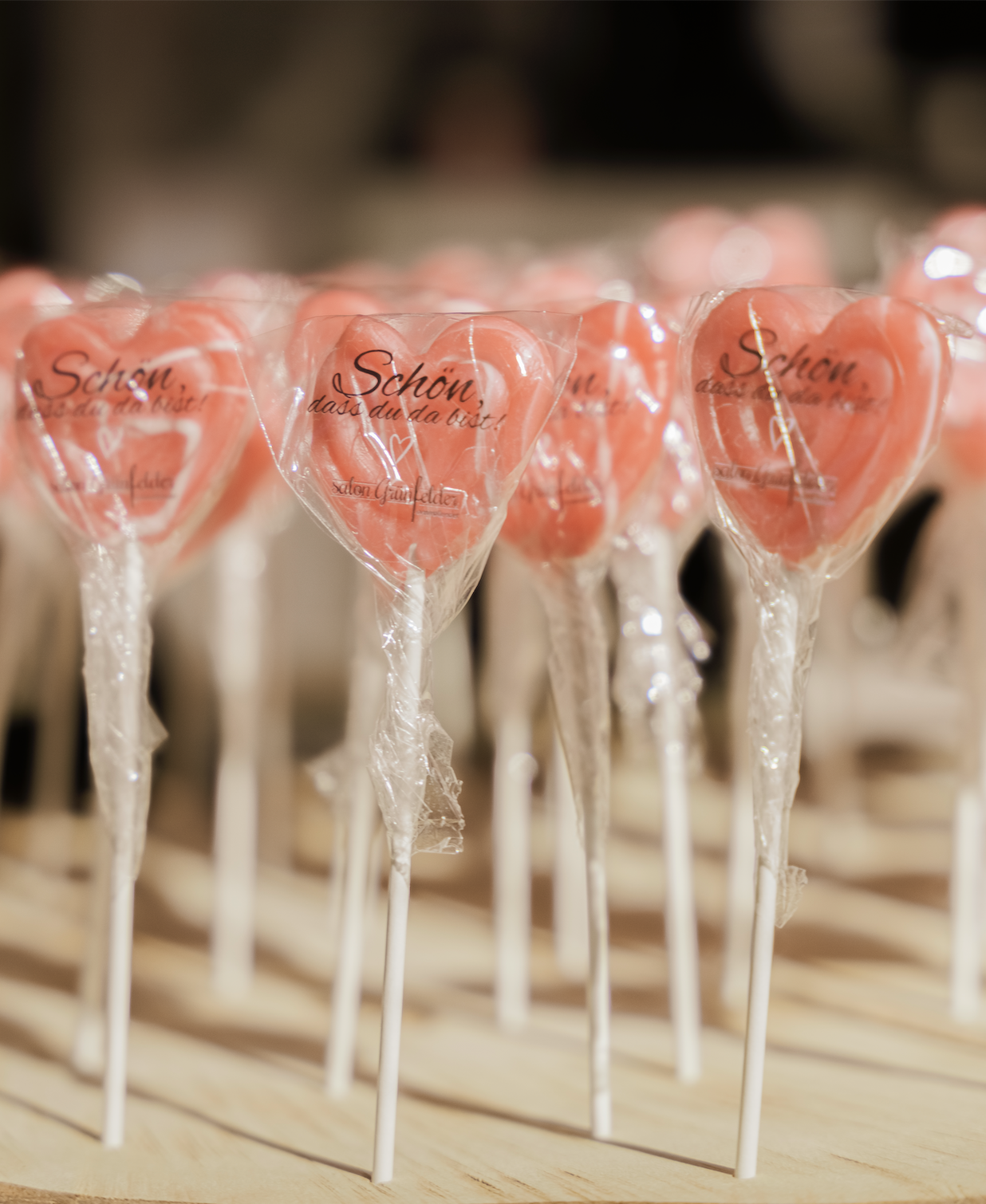 Impressionen des letzten Mädelsabends: rosa Herz-Lollis in transparent Kunststoffverpackungen auf Holz.