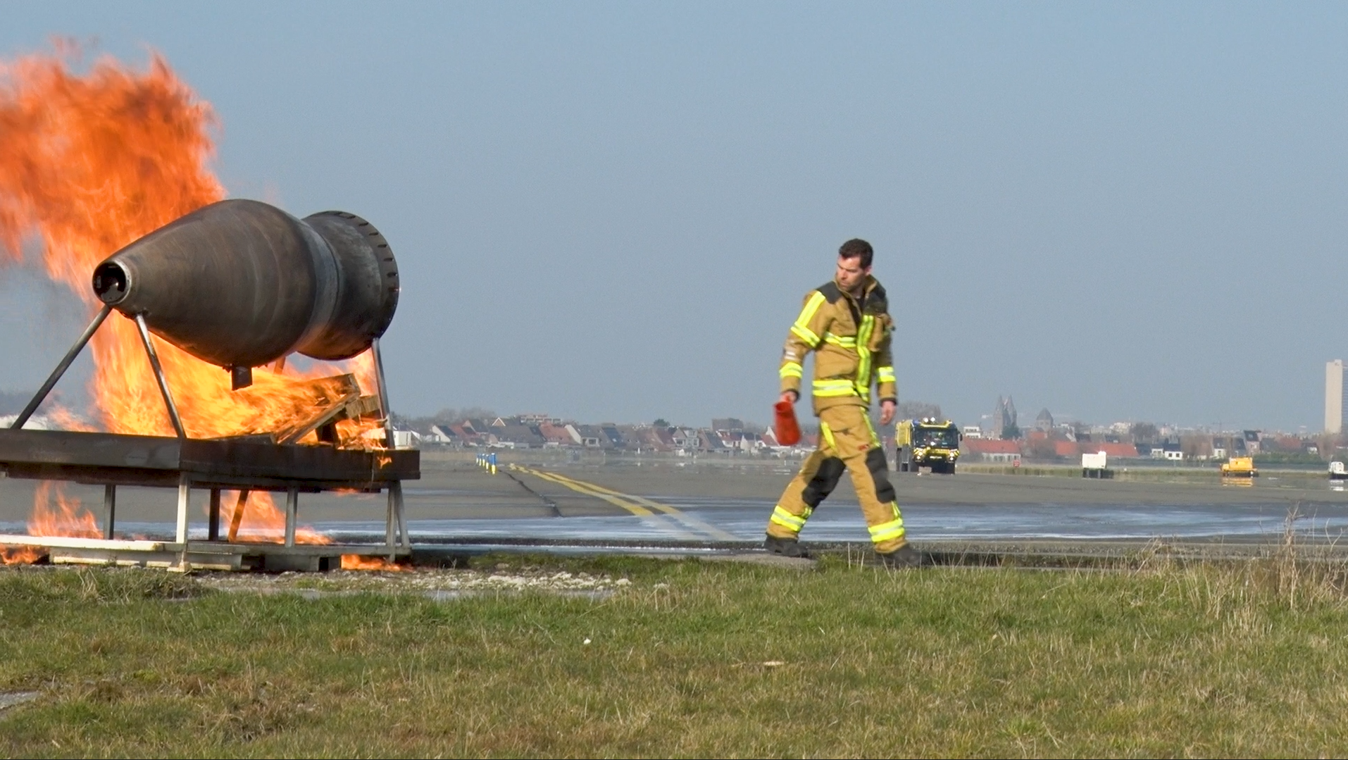 A firefighter walking on an airfield near a burning missile.