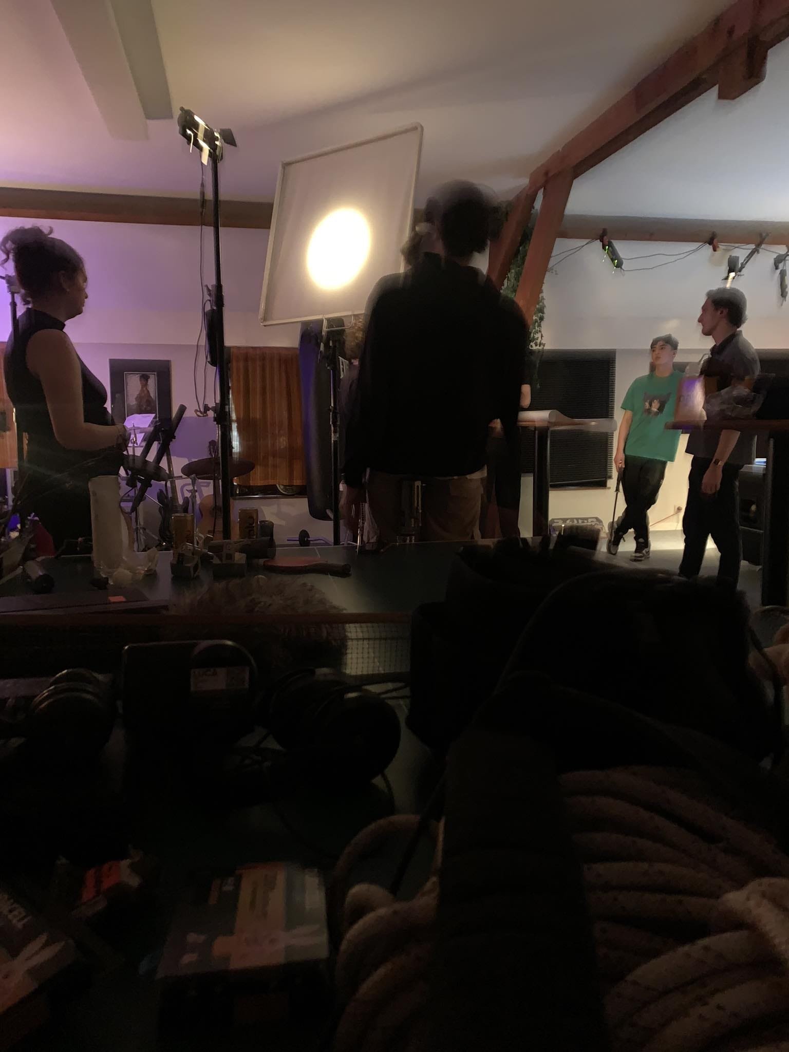 Behind the scenes of a filming set showing crew members, lighting equipment, and people preparing for a shoot indoors.