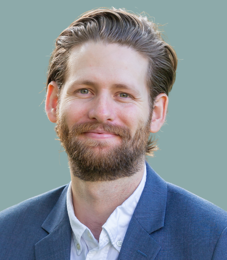 Headshot of Hunter Sims, wearing a white shirt and blue blazer, smiling against a neutral background.