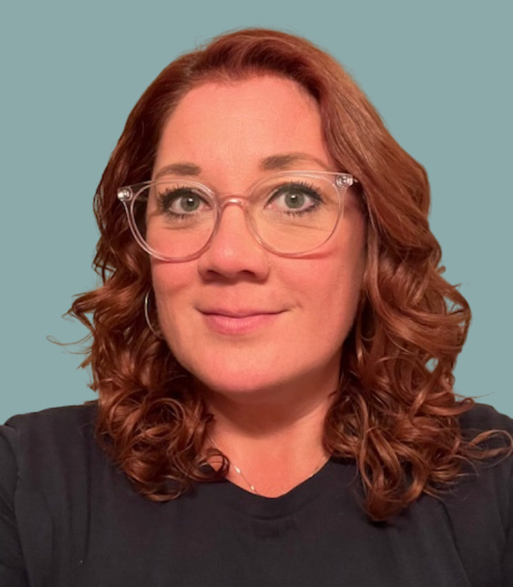 Photo of Lucy, smiling against a light teal background.