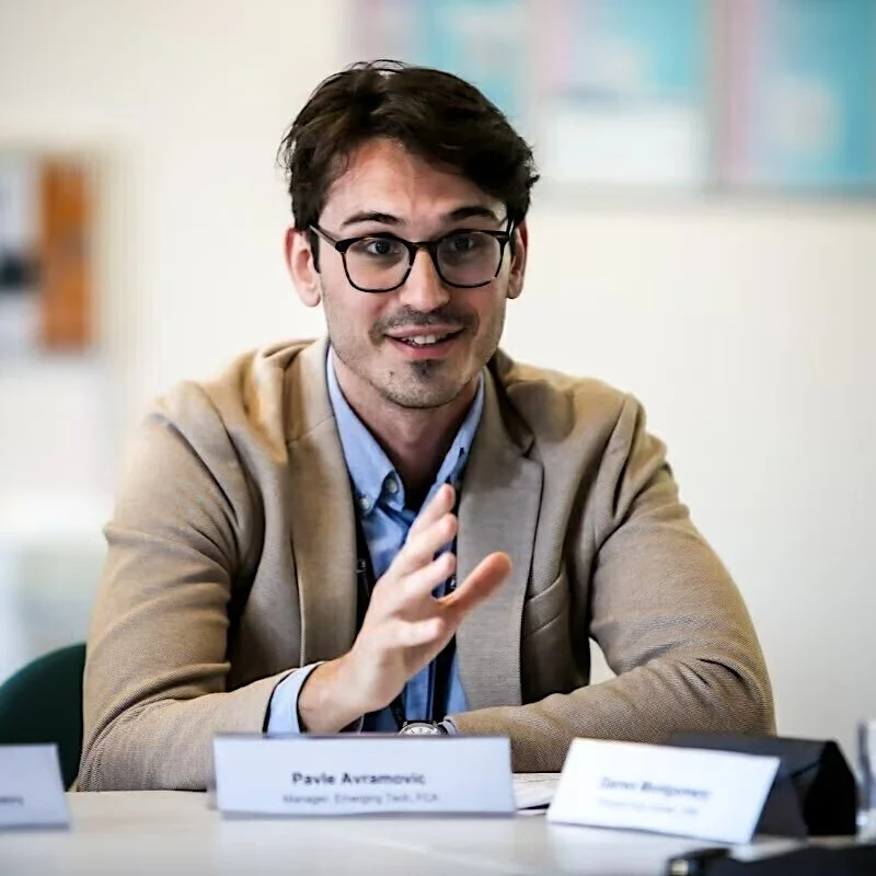 Photo of Pavle, with papers and name plates in front of him in a professional setting.