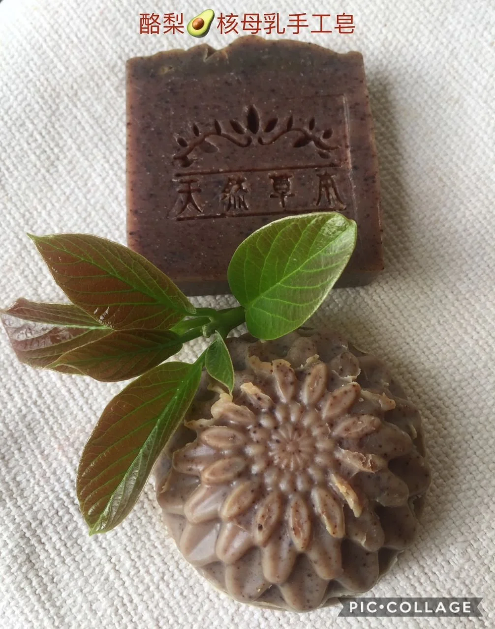 A handmade soap with a carved design, a green leaf, and a textured, spiral-shaped soap on a white fabric background.