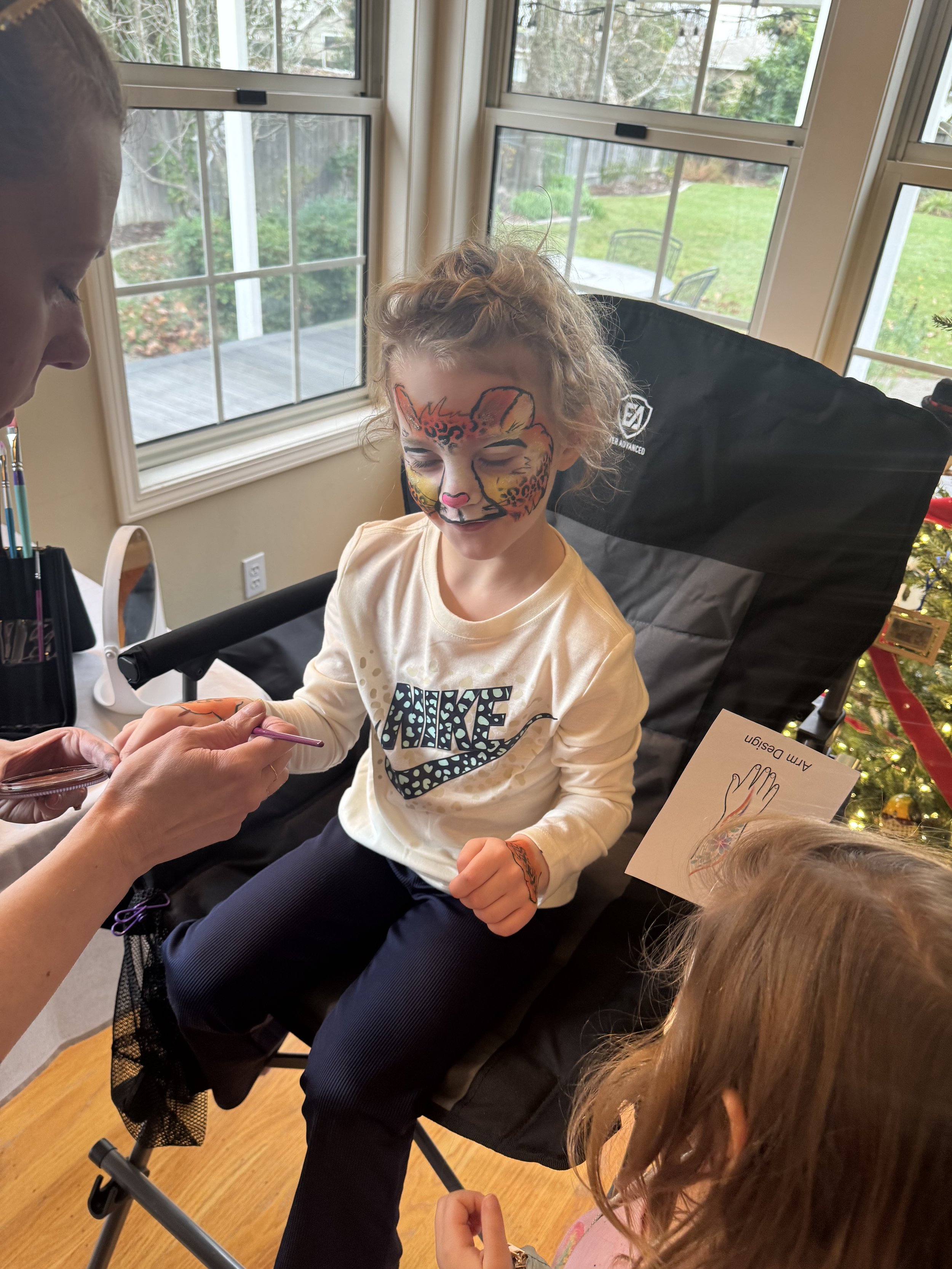 A birthday kid getting matching paws for her face paint.