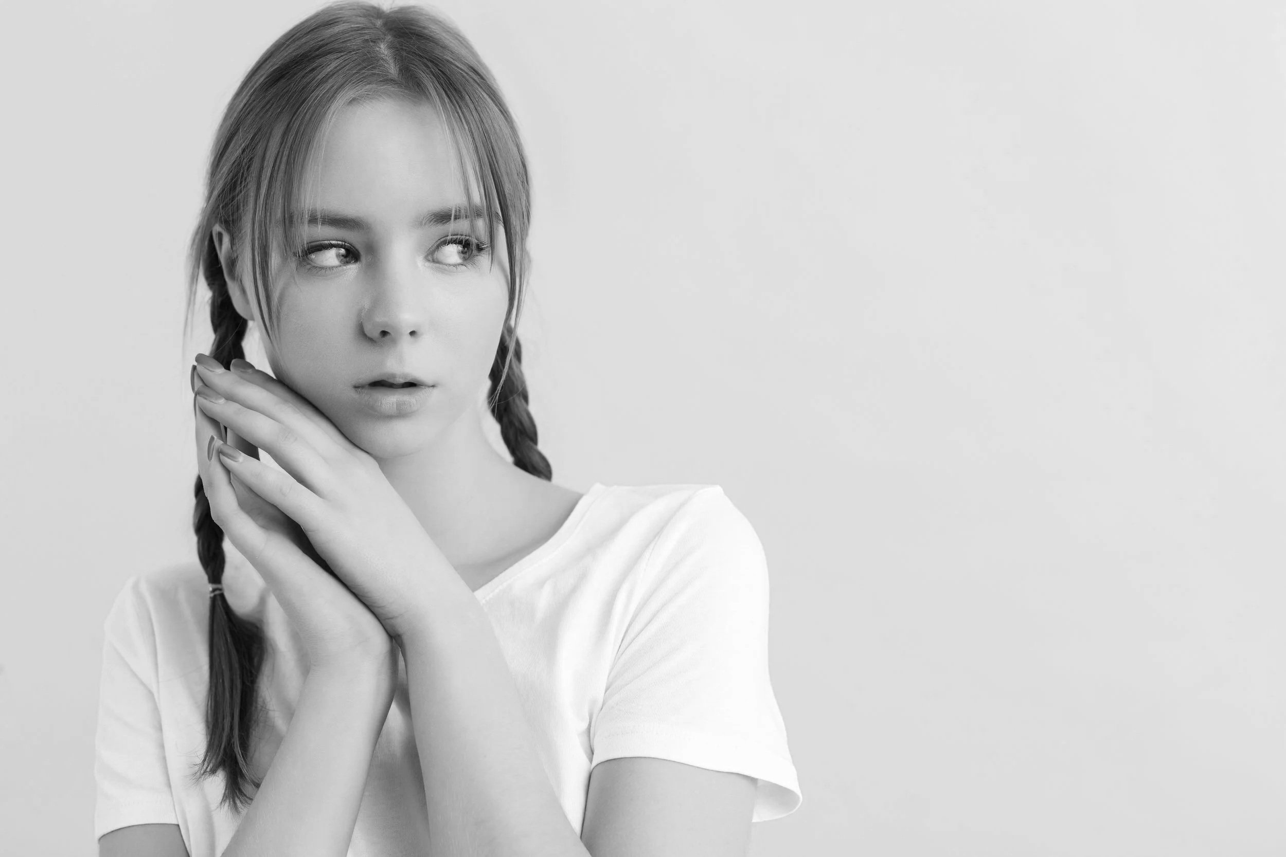 Black and white photo of a teen girl with braided hair, looking to her right, wearing a white t-shirt.