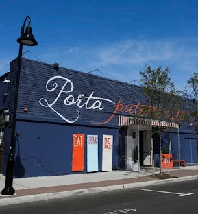 Exterior view of Porta Restaurant with colorful signage and outdoor seating under a blue sky.
