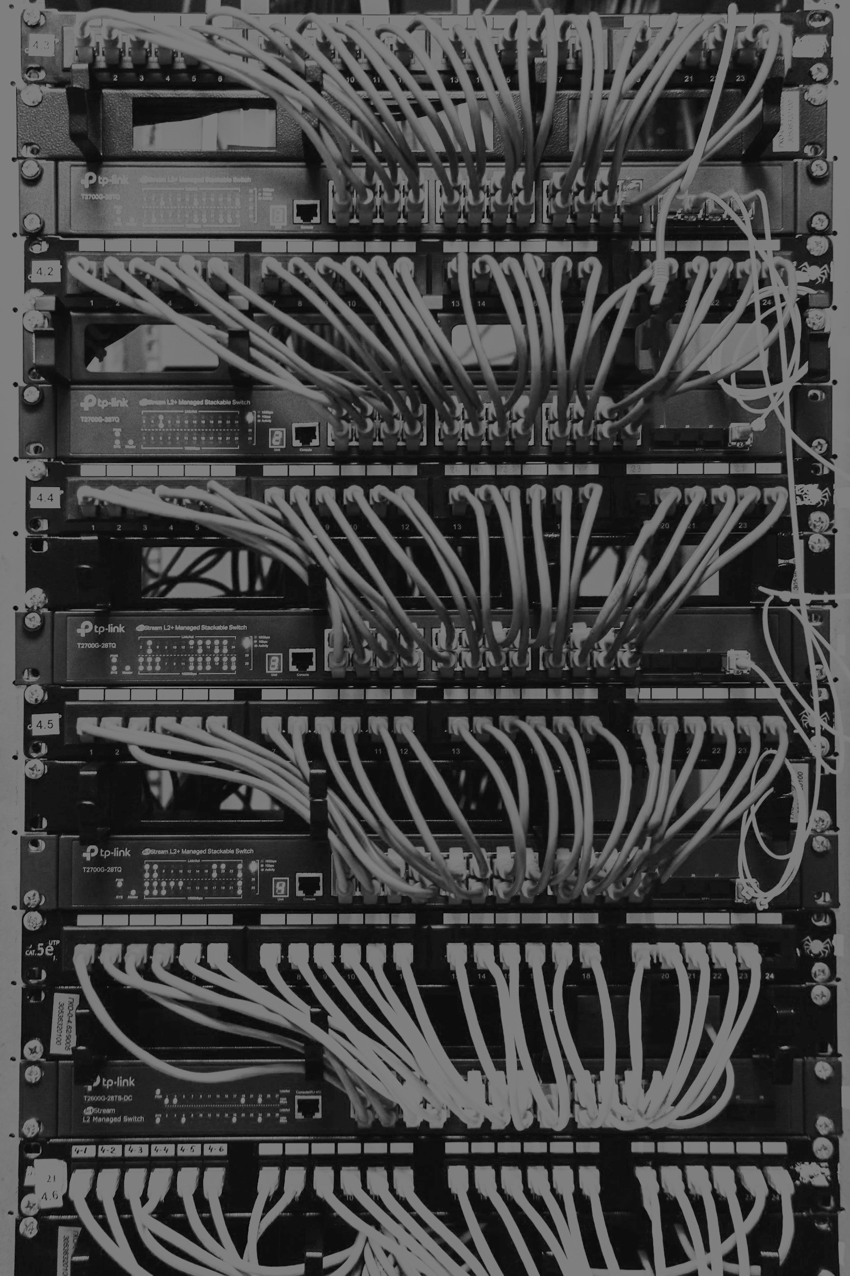 Black and white photo of a server rack filled with multiple network switches and organized cabling.