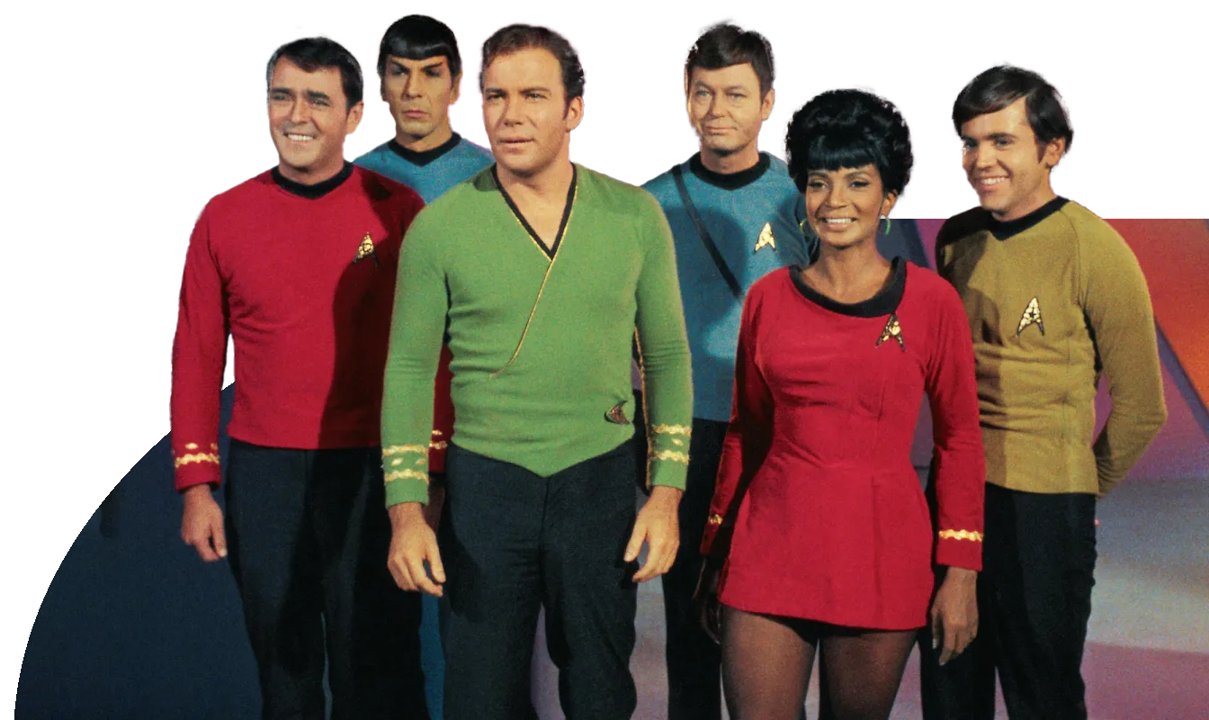 Group photo of six individuals in Star Trek uniforms from the original series, featuring three men and one woman, indoors with a colorful background.