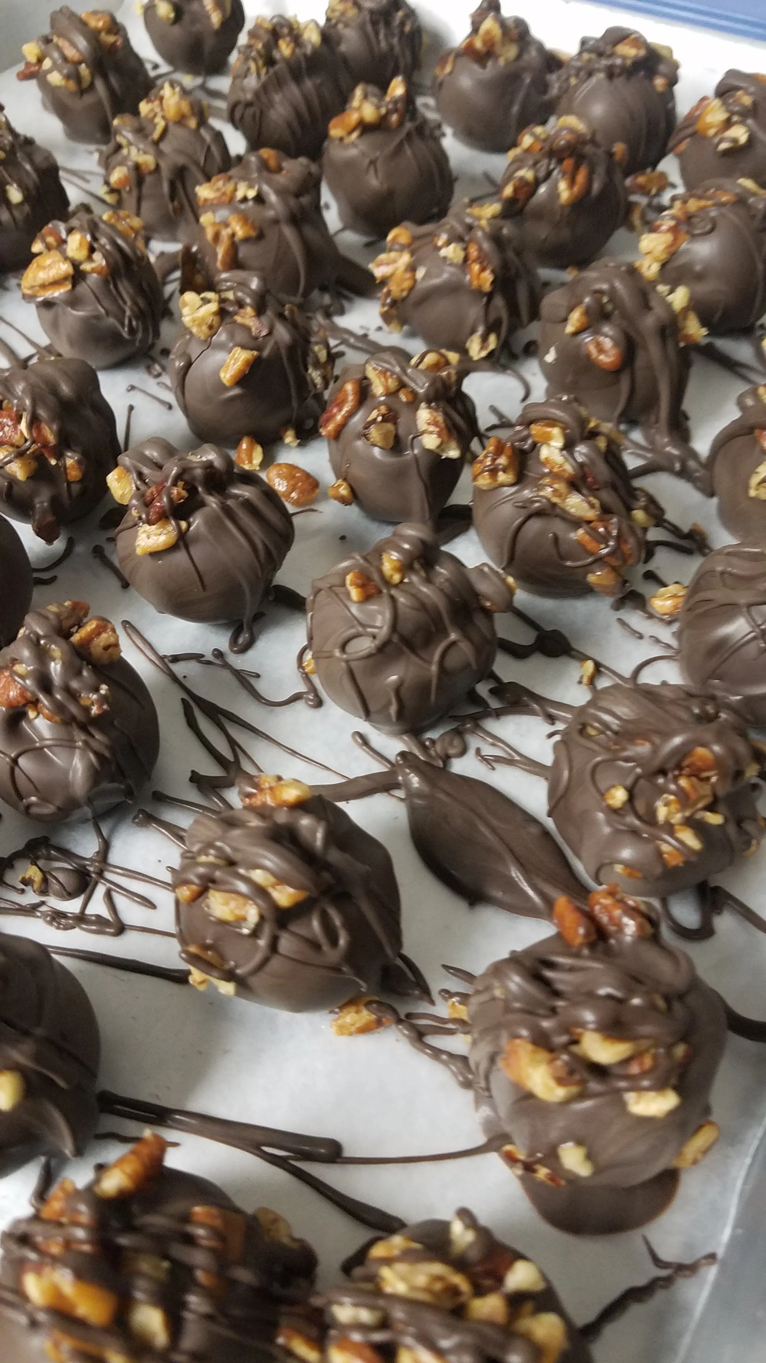 Dark Chocolate pecan fudge truffles topped with chopped pecans, drizzled with additional chocolate.