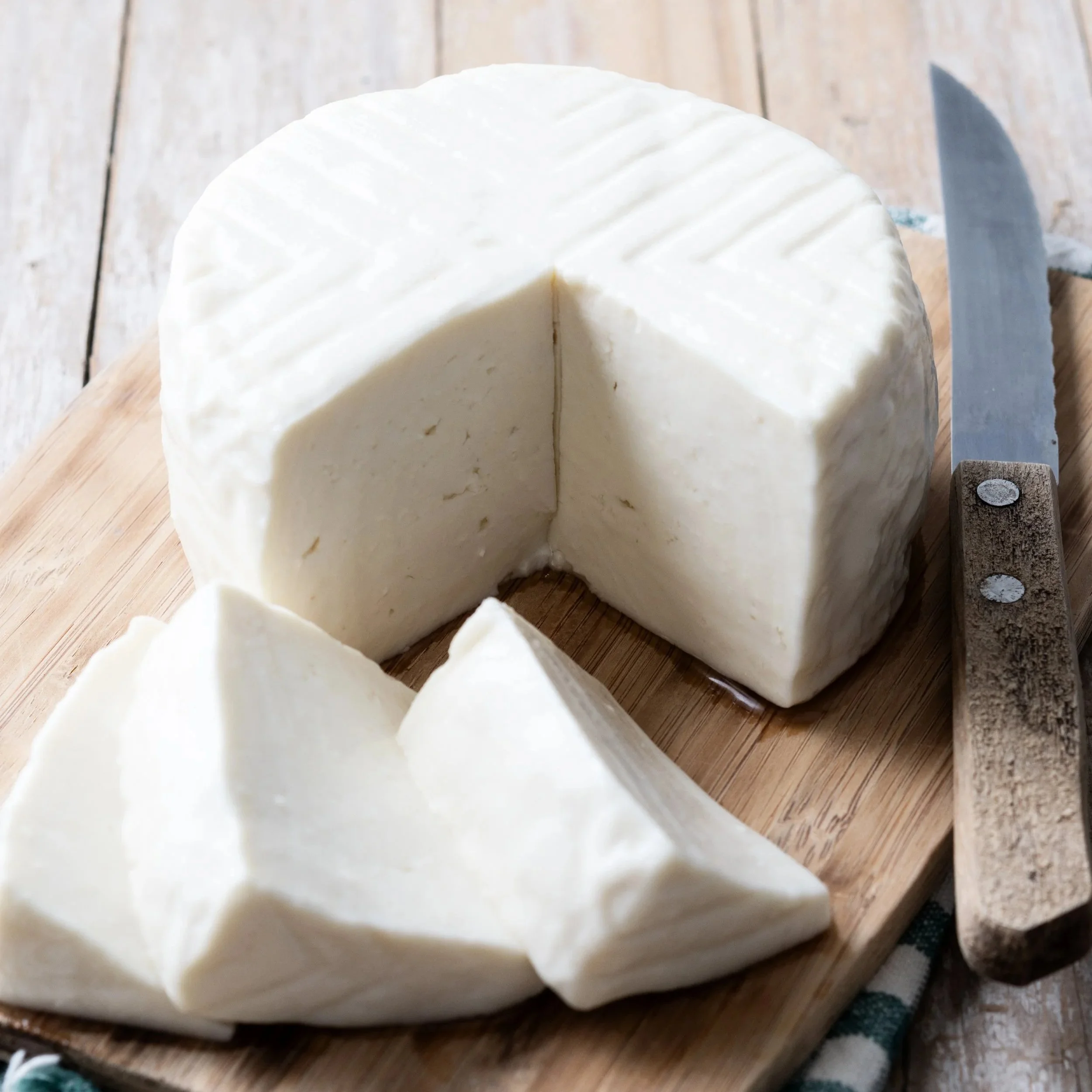Fromage blanc ou quark sur une planche en bois, avec un couteau à côté.