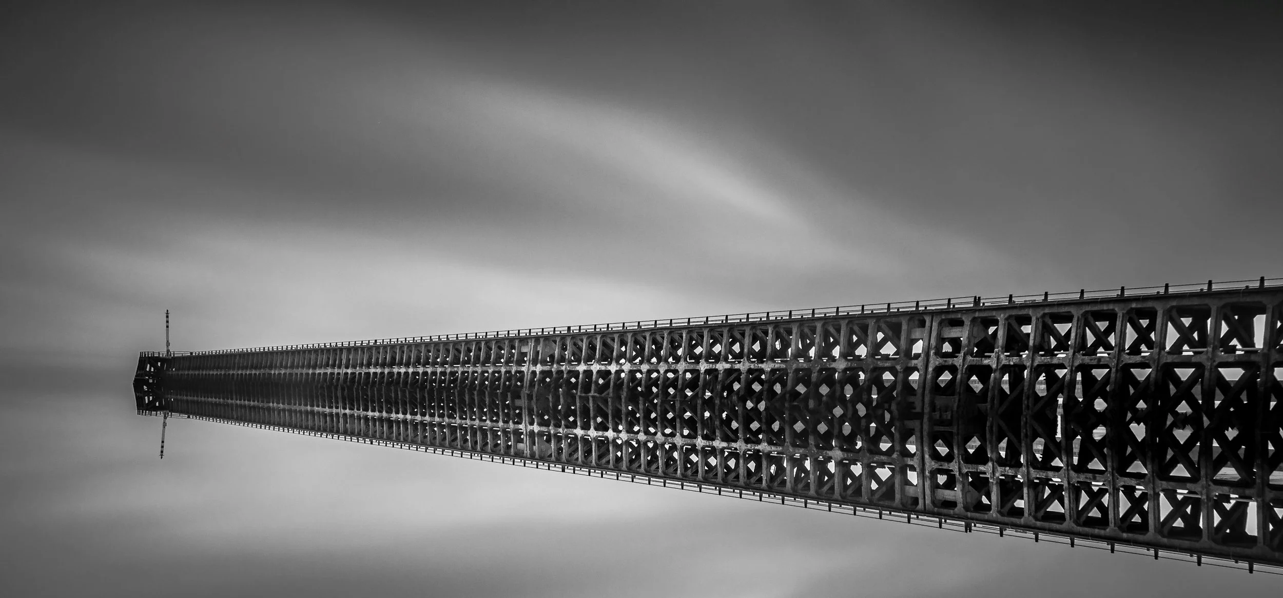 Black and white photo of a tall, lattice steel tower extending into the sky.