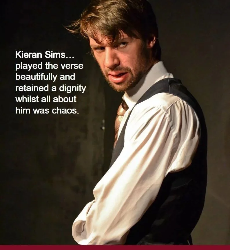 A man with brown hair and beard, wearing a white shirt, black vest, and tie, looking at the camera with a serious expression against a dark background. Text overlay says, "Kieran Sims... played the verse beautifully and retained a dignity whilst all 