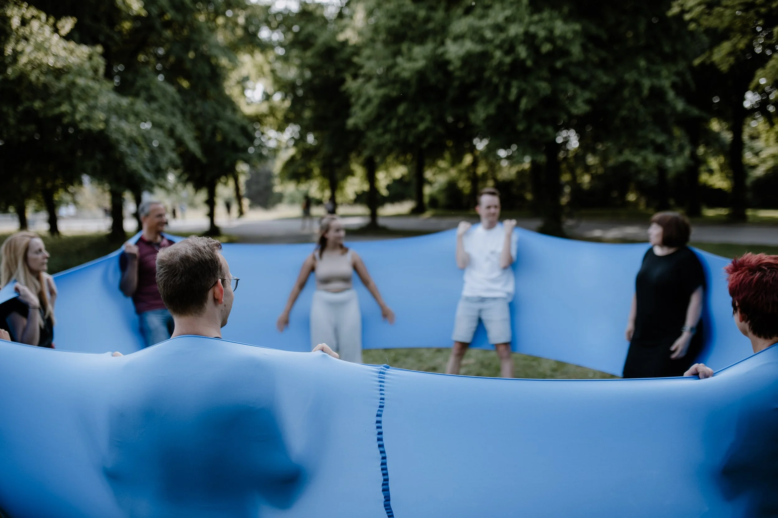 Menschen, die im Park mit einem blauen Schleier spielen.