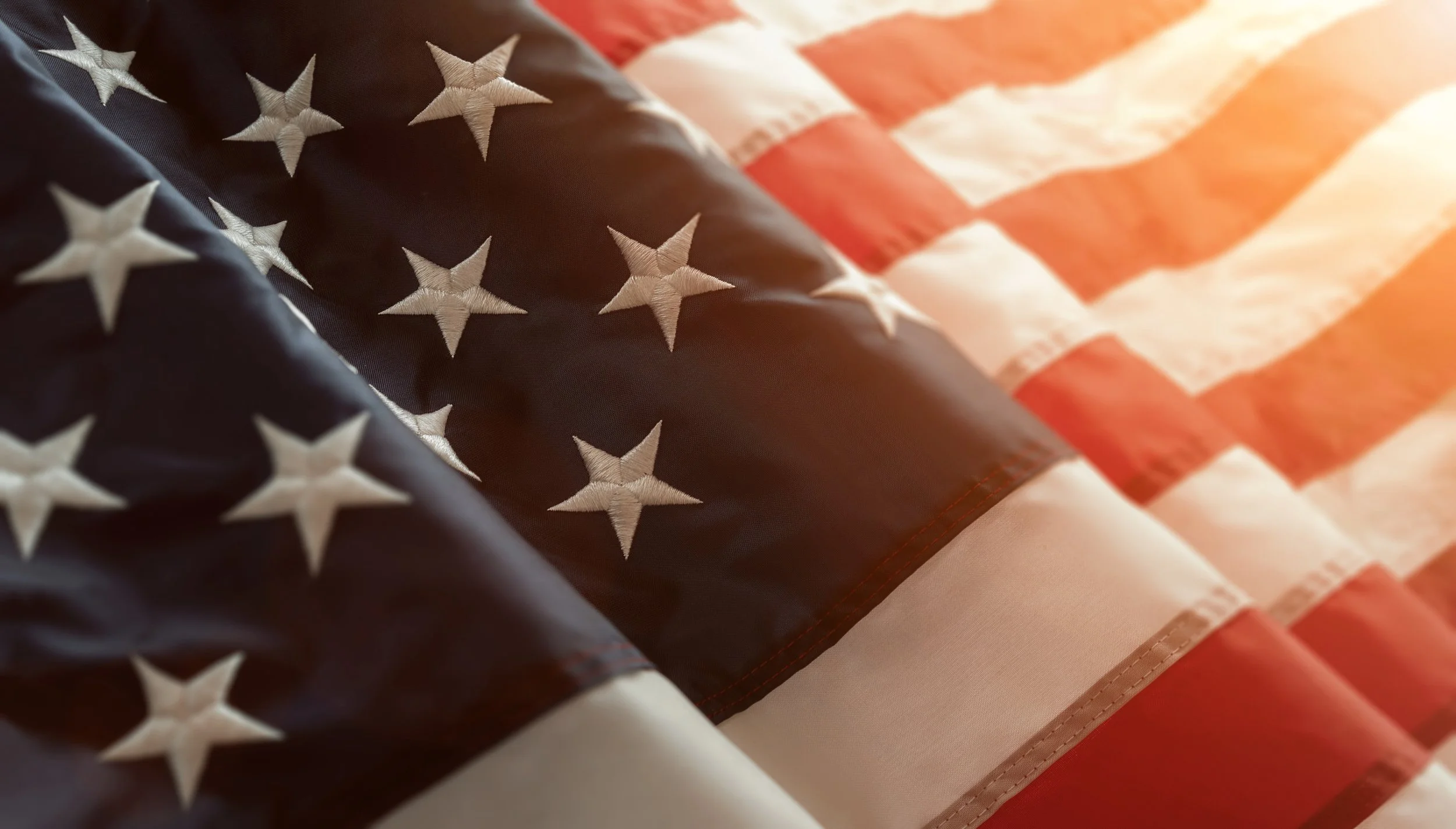 Close-up of an American flag with stars and stripes, showing detailed embroidery and vibrant colors.
