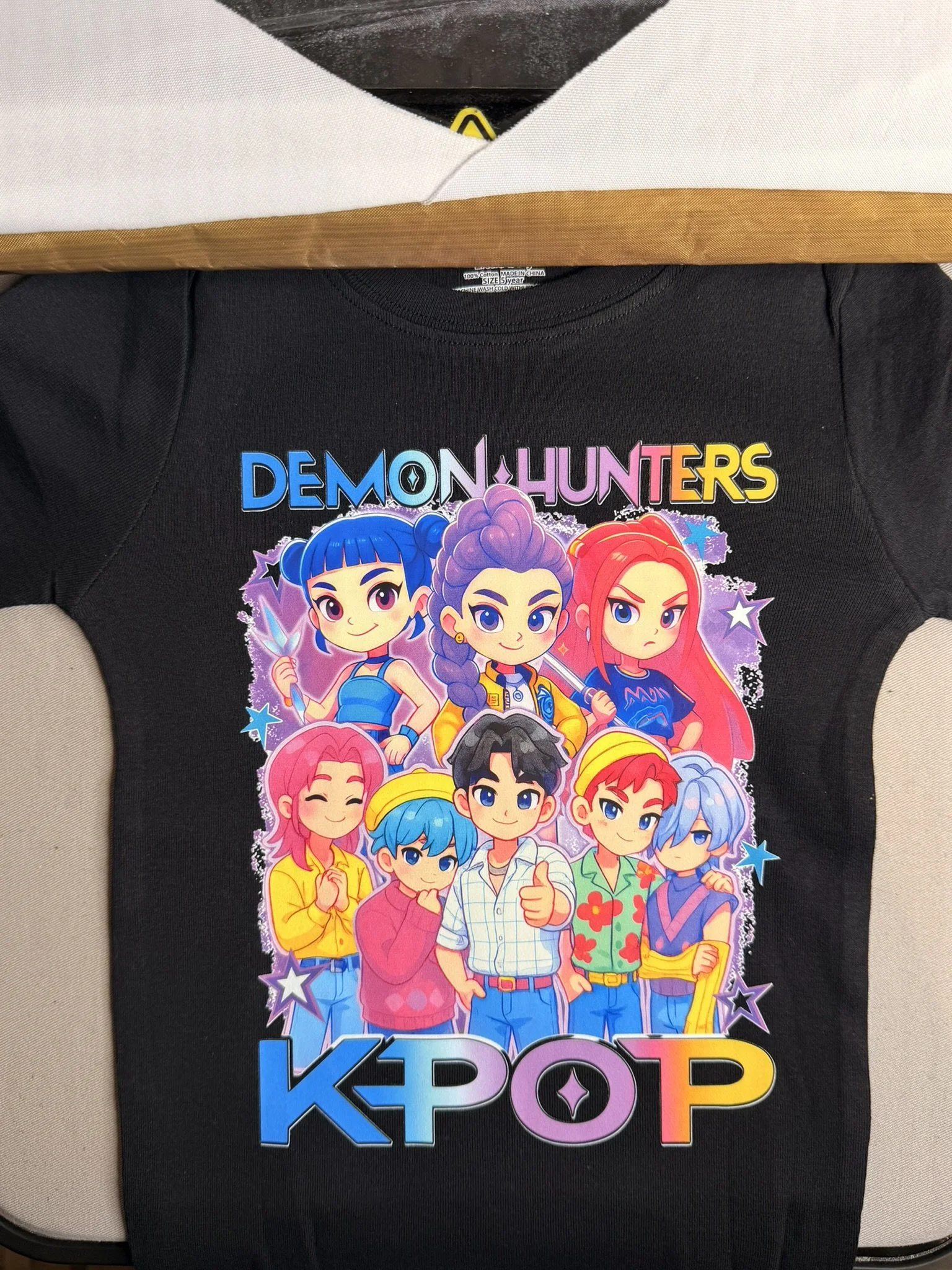 Colorful cartoon-style illustration of nine diverse characters from the K-pop style girl group, with vibrant hairstyles and outfits, under the words 'Demon Hunters' and 'KPOP'.