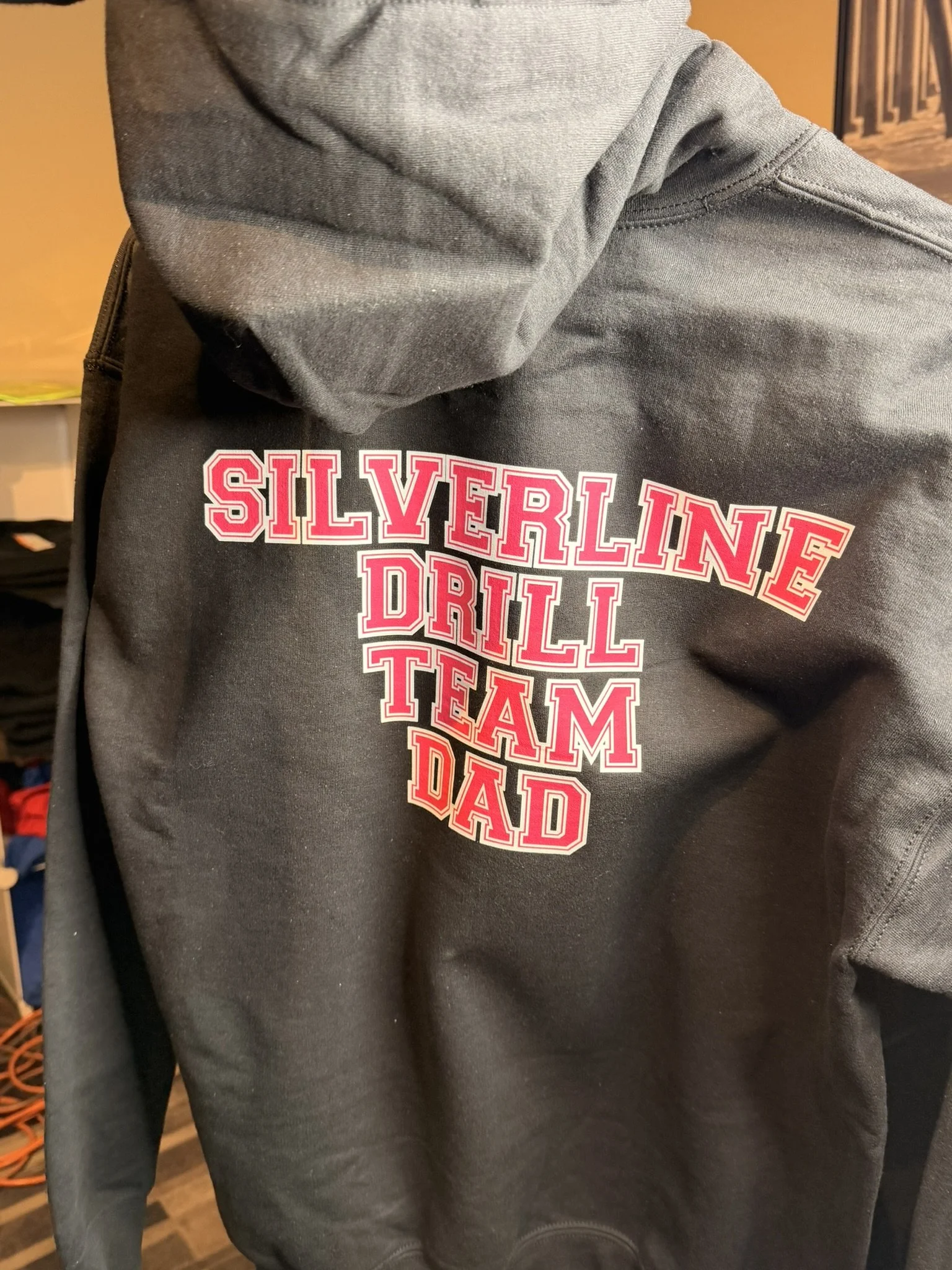 Black hoodie with red and white text that reads 'Silverline Drill Team Dad'