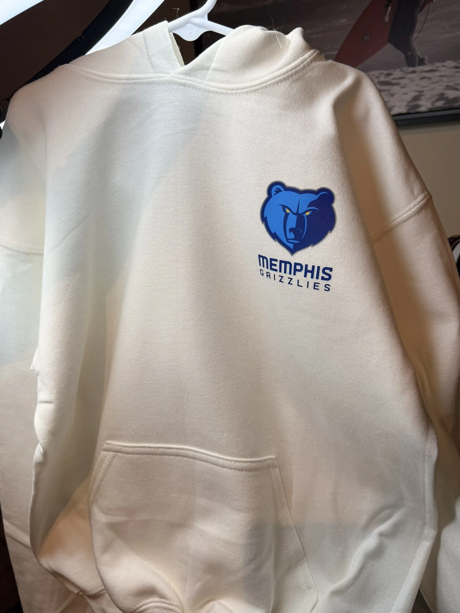 A white hoodie with a blue Memphis Grizzlies logo and text on the front, hanging on a white hanger.