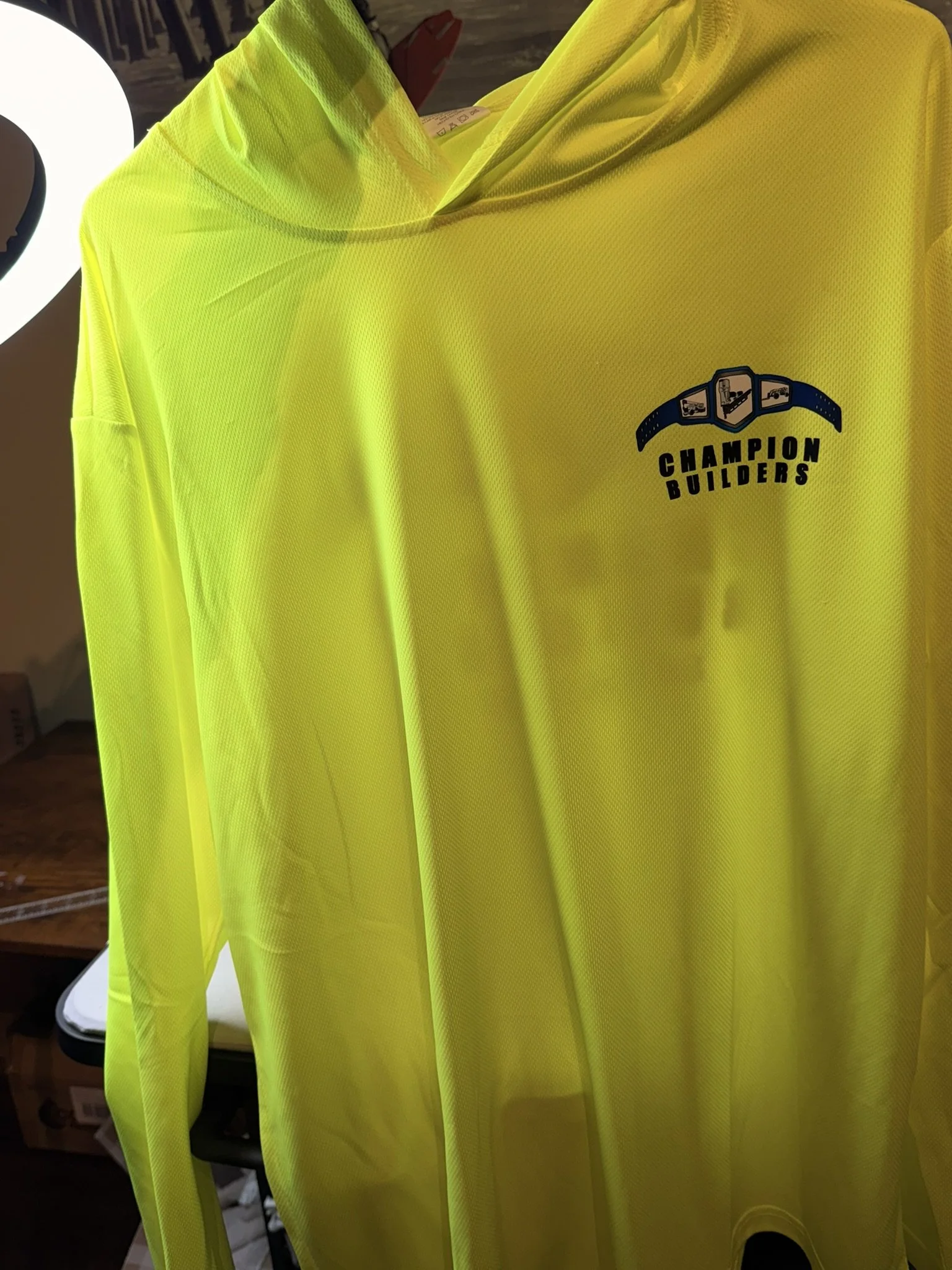 Bright yellow long-sleeve shirt with the logo "Champion Builders" and construction icons on the upper left chest.