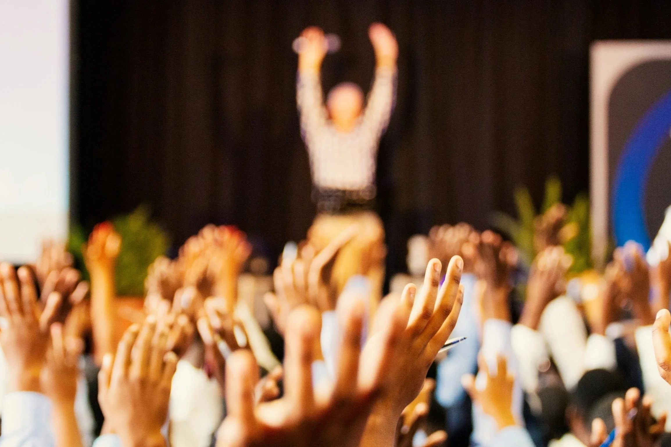A modern wooden house situated on a grassy hillside overlooking a large lake, with mountains in the background and a cloudy sky.