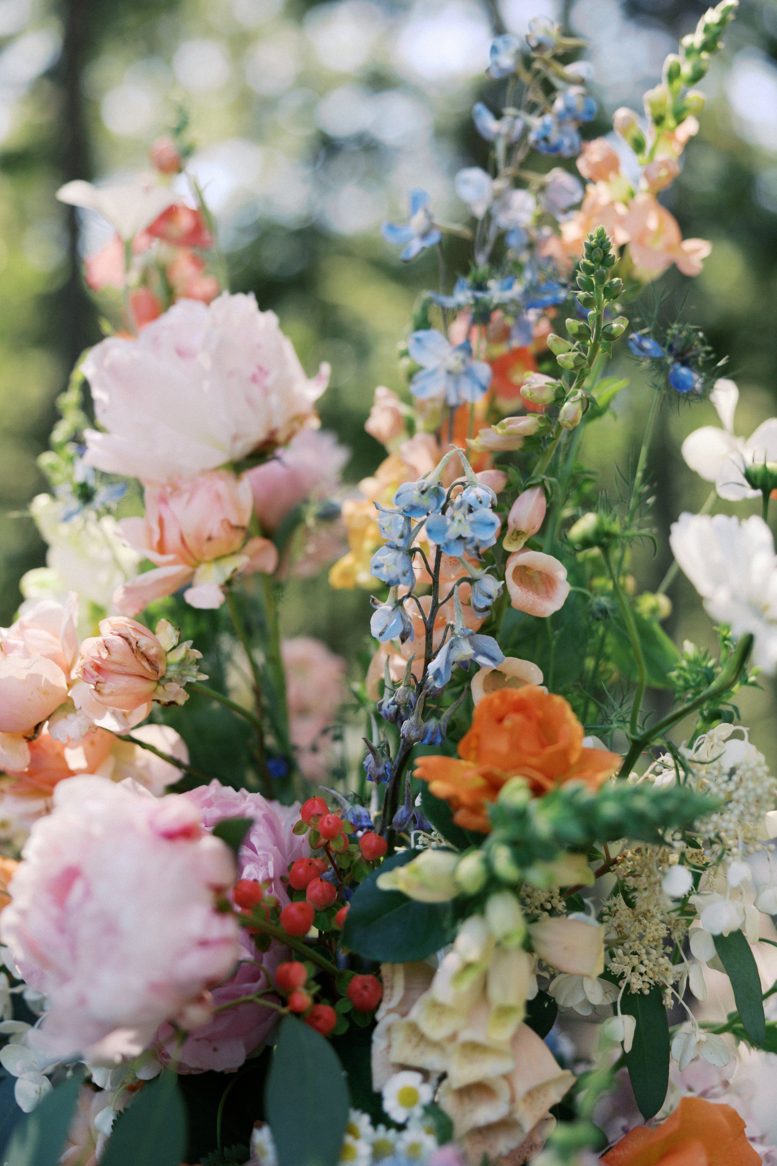 Close-up of colorful flowers, including pink peonies, blue delphiniums, orange roses, and white cosmos, with greenery.

Photo by Here Today Photography
Venue: Rocky Hill Weddings & Events in White Salmon, WA