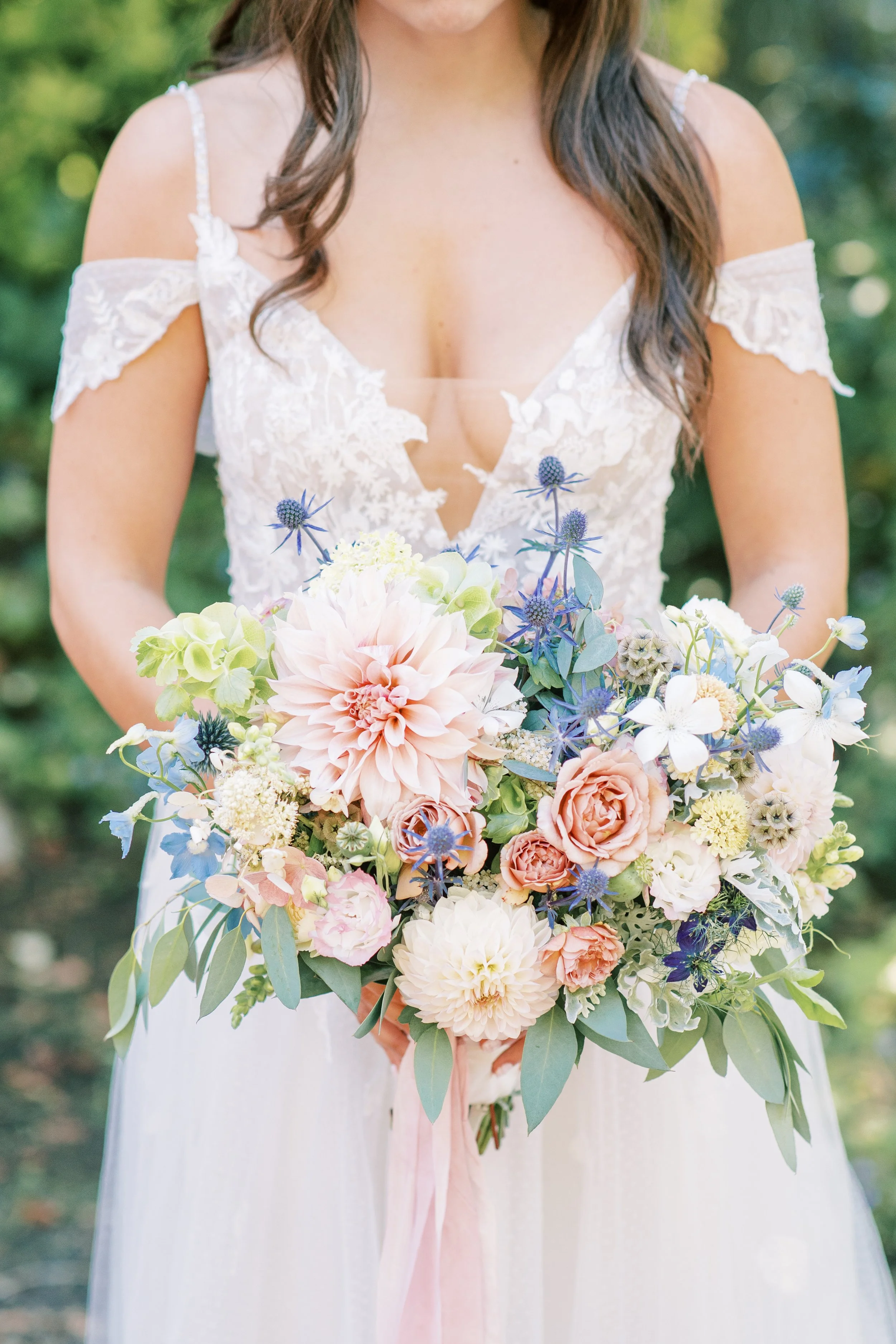 A woman in a lace wedding dress holding a large bouquet of pastel-colored flowers and greenery.

Photo by McKenna Rachelle Photography
Venue: The Oregon Gardens in Springfield, OR