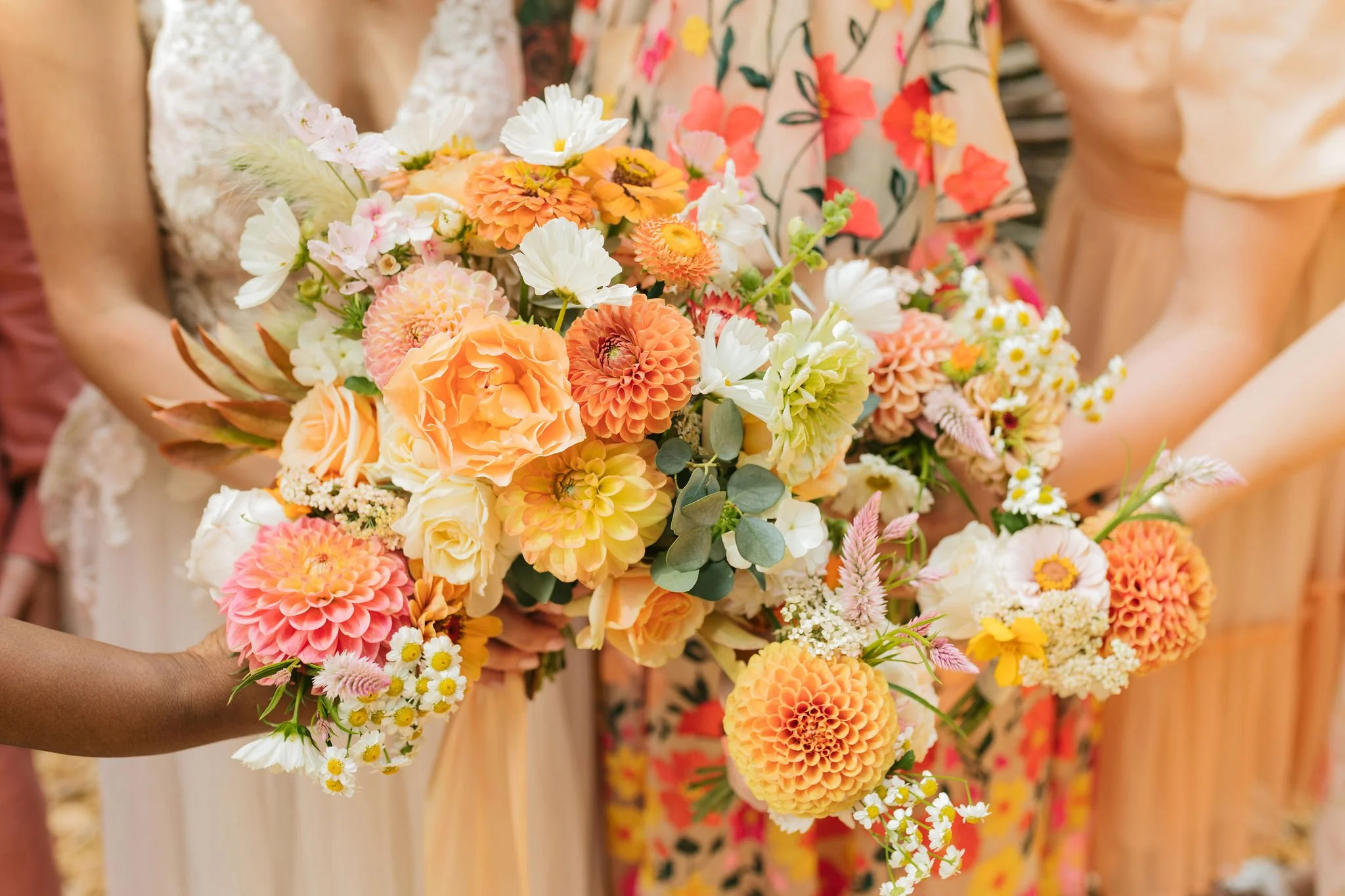 A group of women holding colorful bouquet of flowers in peach, yellow, white, and pink shades with a background of floral dresses.

Photo by Char Marl Photography
Venue: The Aerie at Eagles Landing in Happy Valley, OR