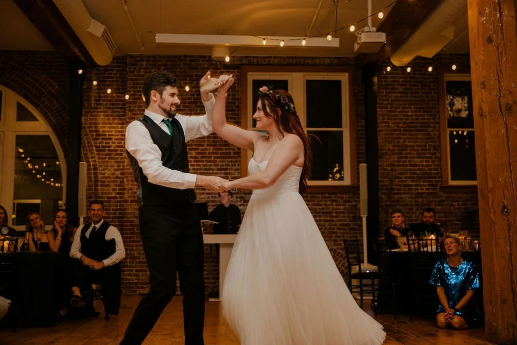 A bride and groom dance at their wedding reception in a industrial modern venue with brick walls and warm lighting.

Photo by Ronny & Rene
Venue: Ecotrust Events Irving Street Studio in Portland, OR