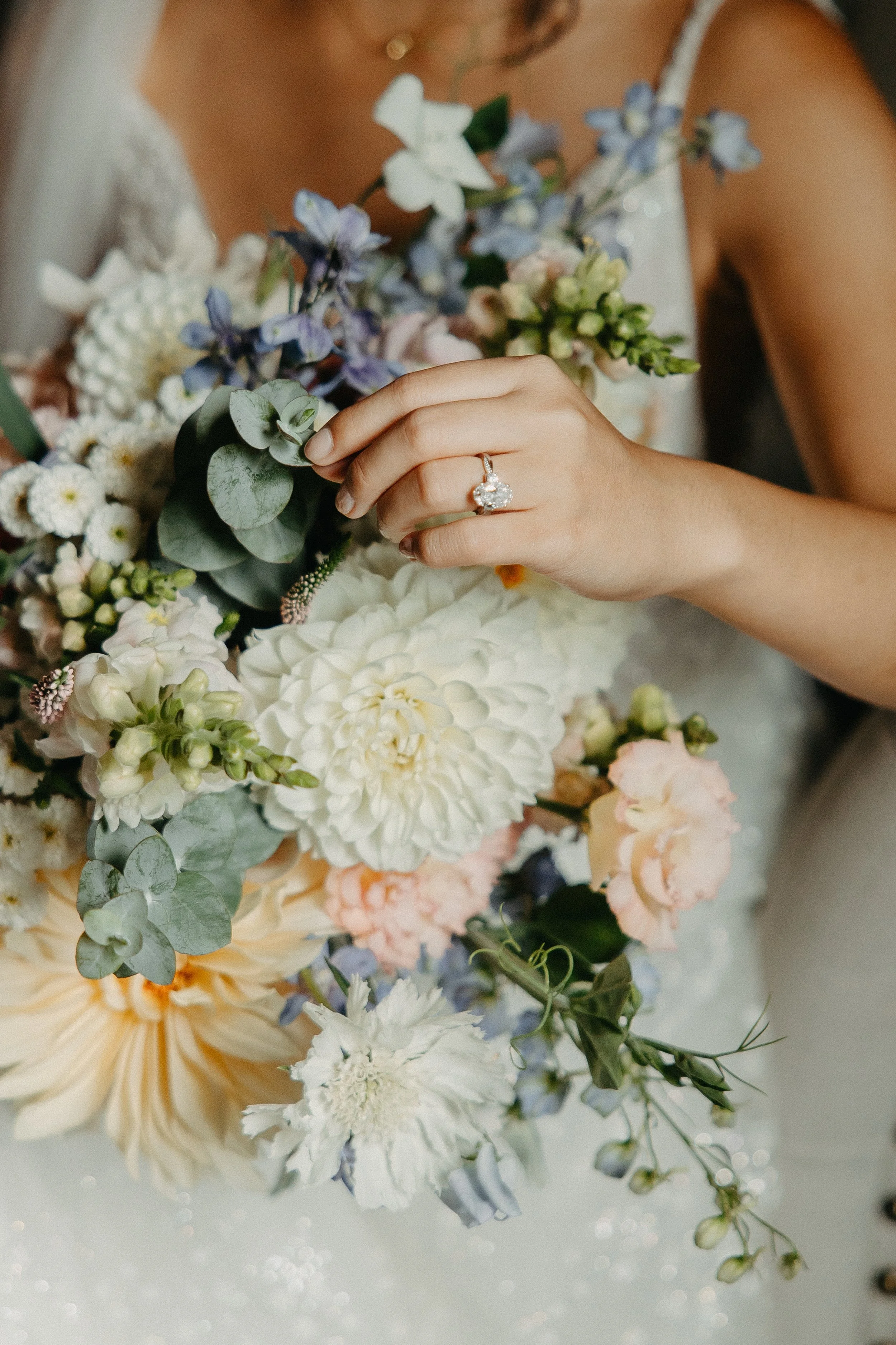 Close-up of a woman's hand with a large diamond engagement ring, holding a bouquet of assorted flowers including white, blue, and pale pink blooms, with greenery.

Photo by Go Lovin Co
Venue: Cape Horn Estates in Stevenson, WA