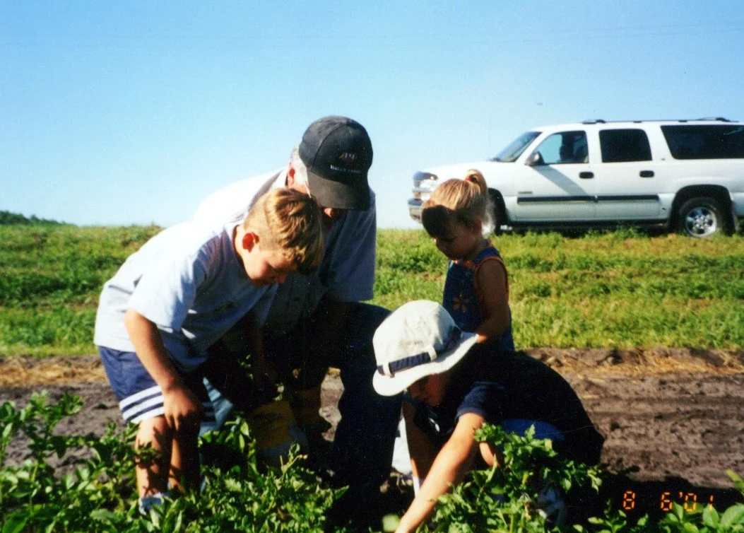 2000s - Sam, Joe, & Mandy Simpson with John Hall in potato field.