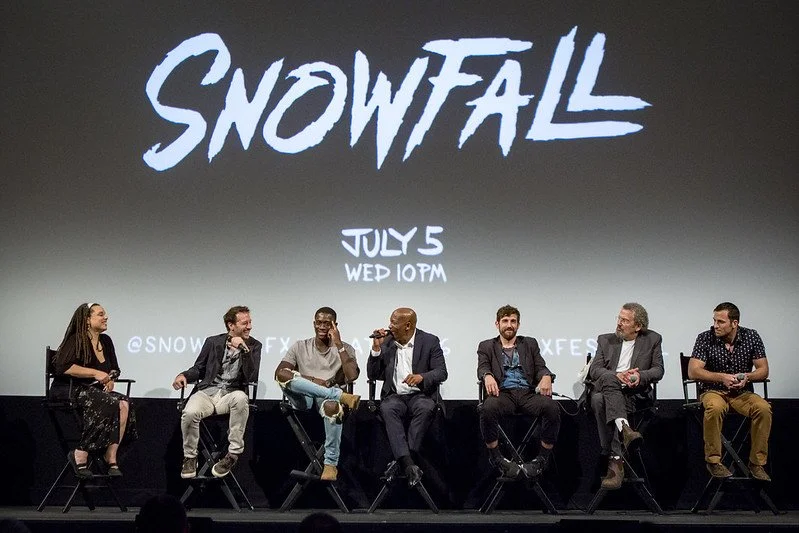 Six people sitting on a stage with a large screen behind them that says "SNOWFALL," and event details for July 5 at 10 PM, with a Twitter handle @SNOWFALLFX."}#}end of response. Please let me know if you'd like a more detailed description!  Alternatively, I can provide a brief summary: This image shows a panel discussion for the show
