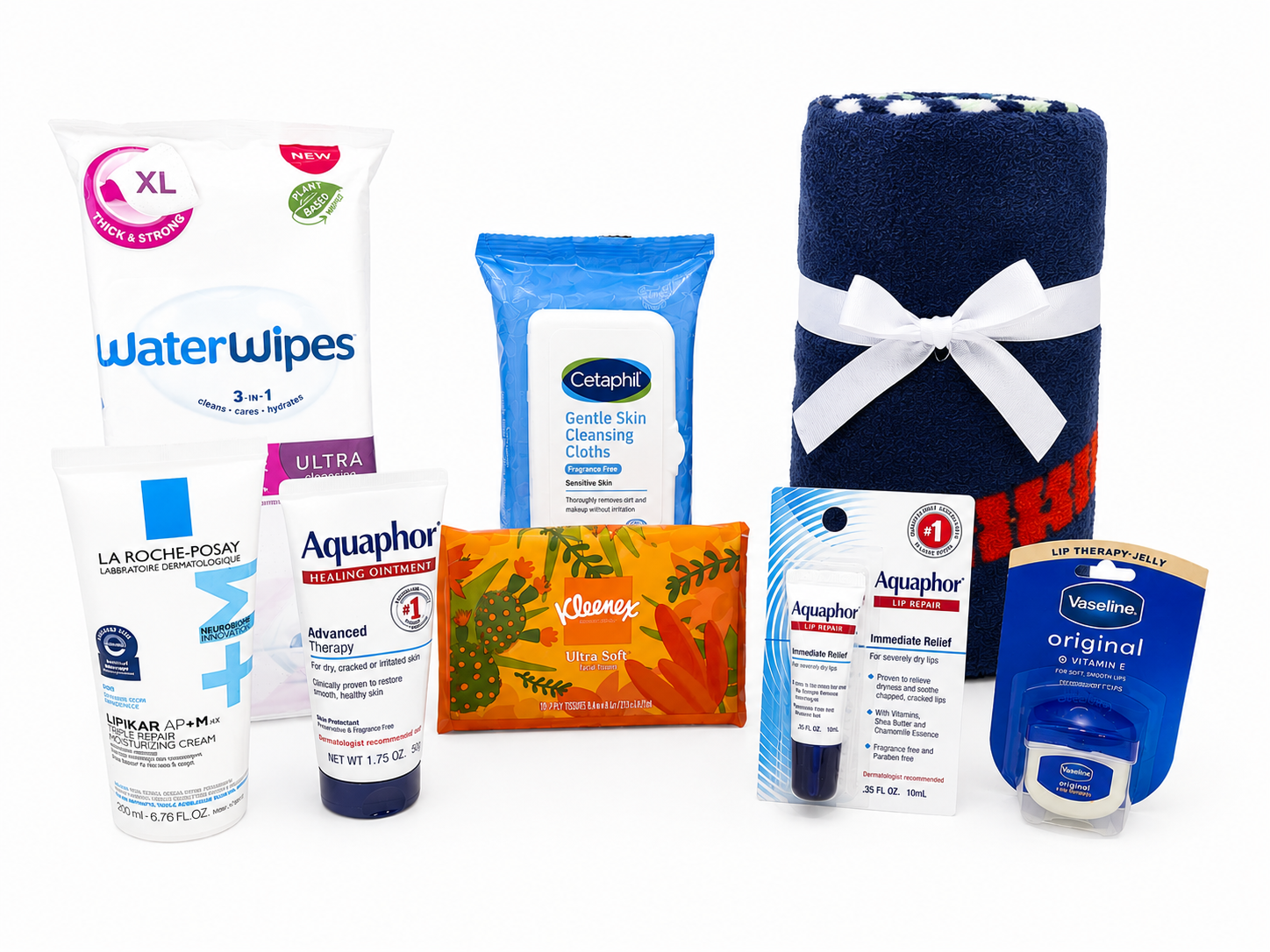 Spa gift set with three rolled towels, facial and body wipes, shampoo, conditioner, body lotion, lip balm, hand soap, and hand cream, arranged on a wooden surface.