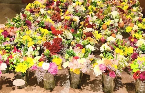 Multiple colorful flower arrangements with various types of flowers in glass vases.