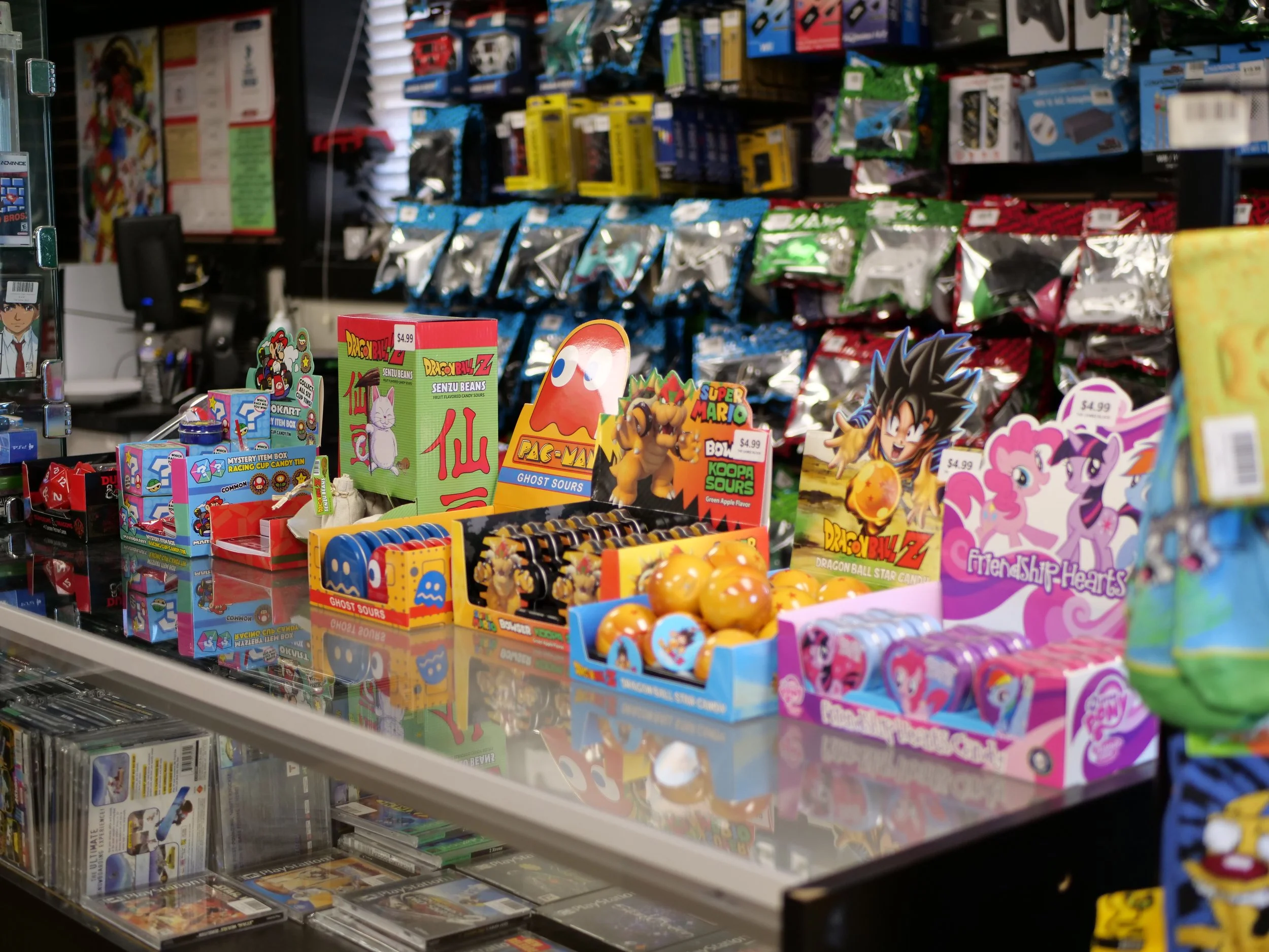 Display of assorted Japanese-themed toys and snacks, including Dragon Ball Z merchandise, Pokémon items, and friendship hearts candies in a retail store.