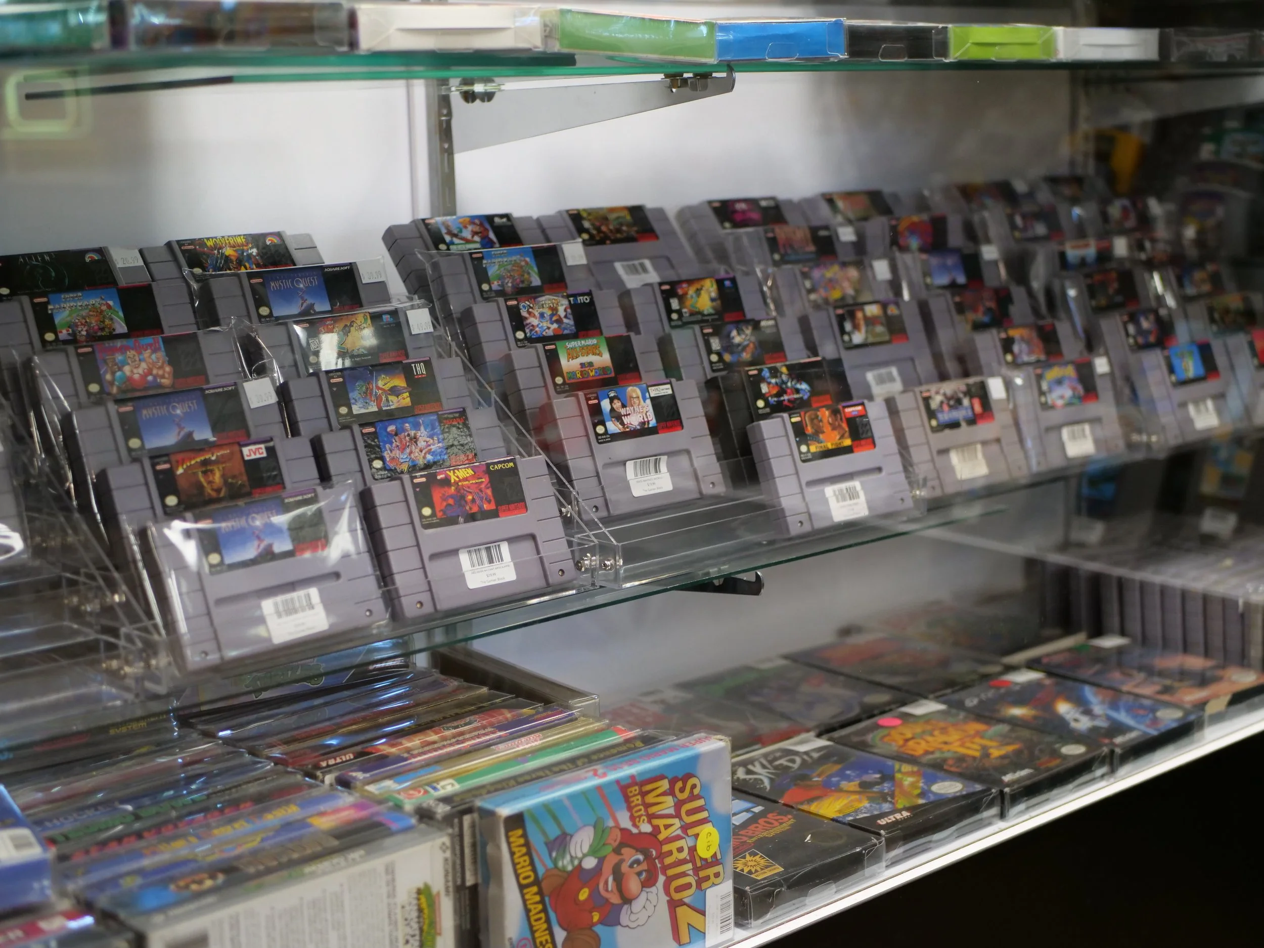 Shelf with classic video game cartridges, including Super Mario Bros., in a store.