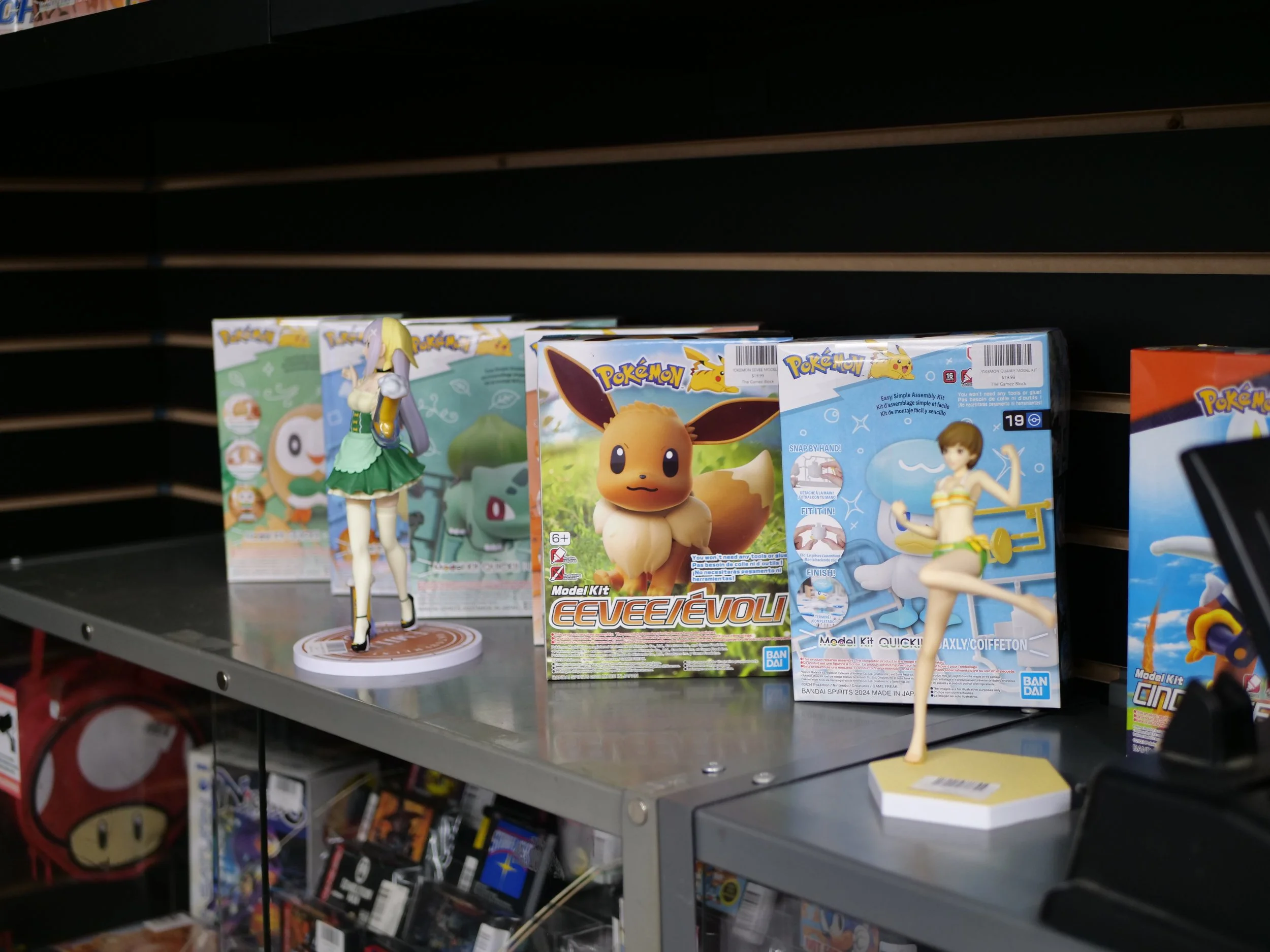Display of Pokémon merchandise including figurines and model kits on store shelf.