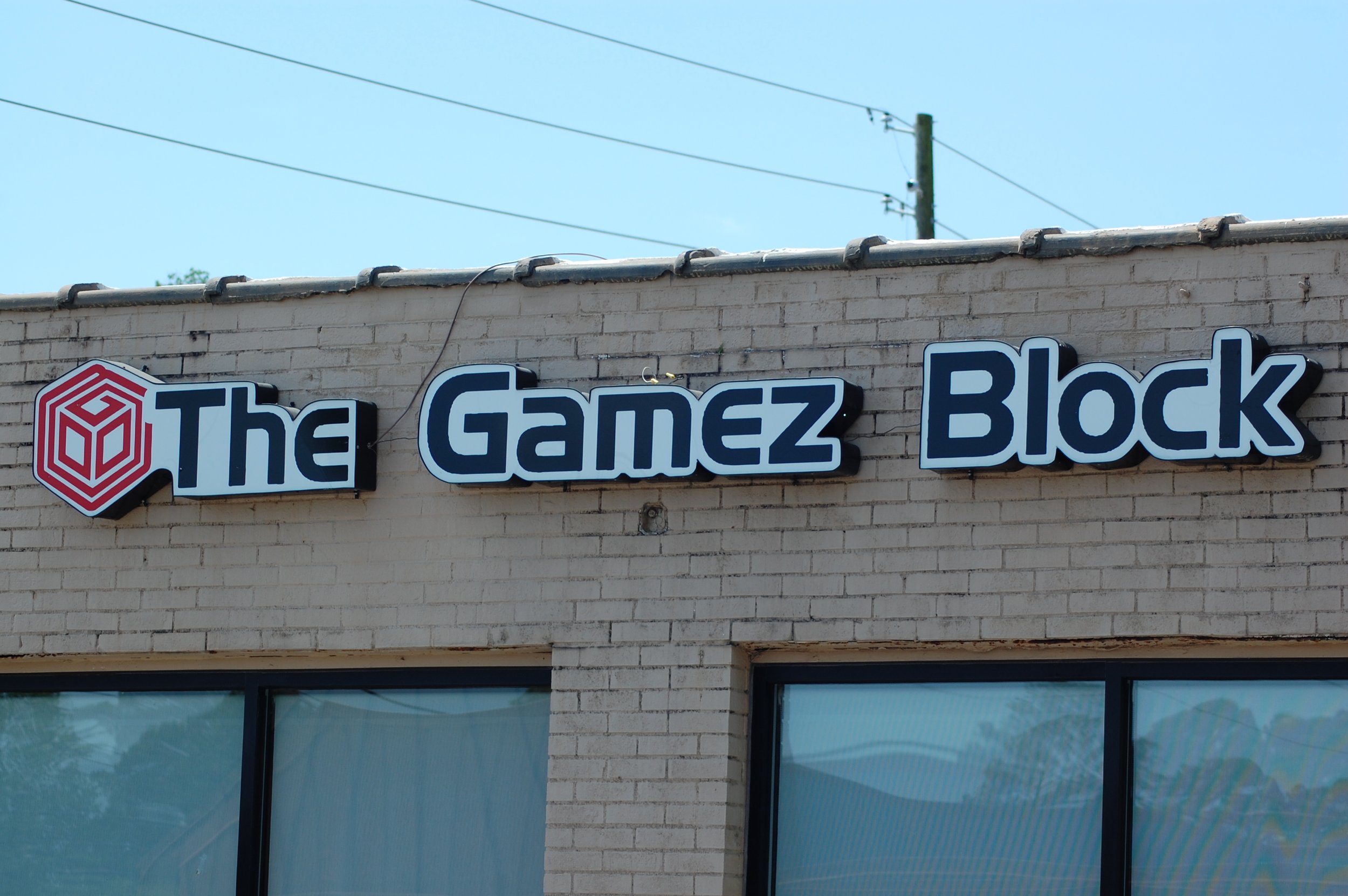 Sign reading 'The Gamez Block' on a brick building with a logo to the left, featuring a red hexagonal icon.