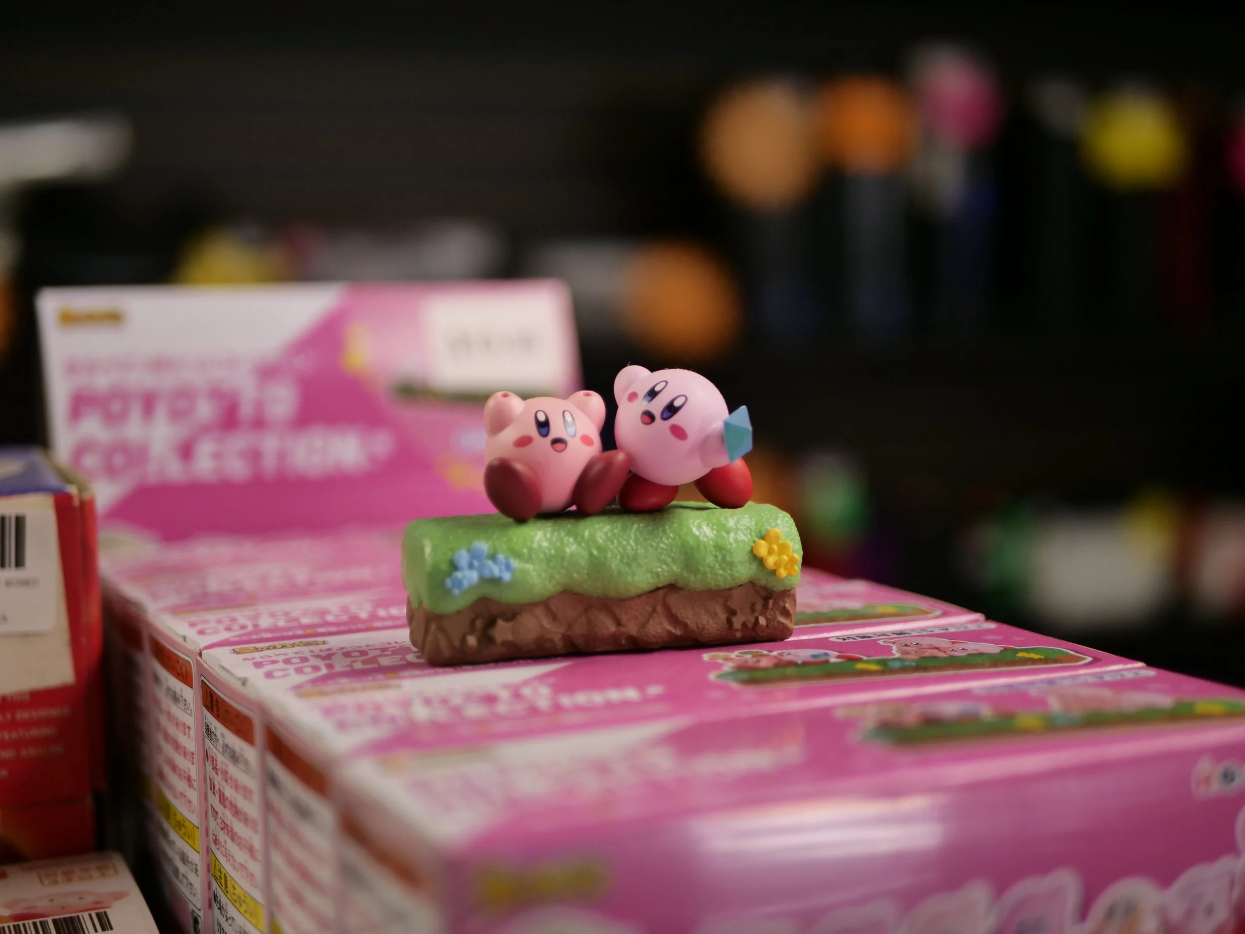 Figurines of Kirby and Waddle Dee from Nintendo's Kirby series sitting on a colorful toy box.