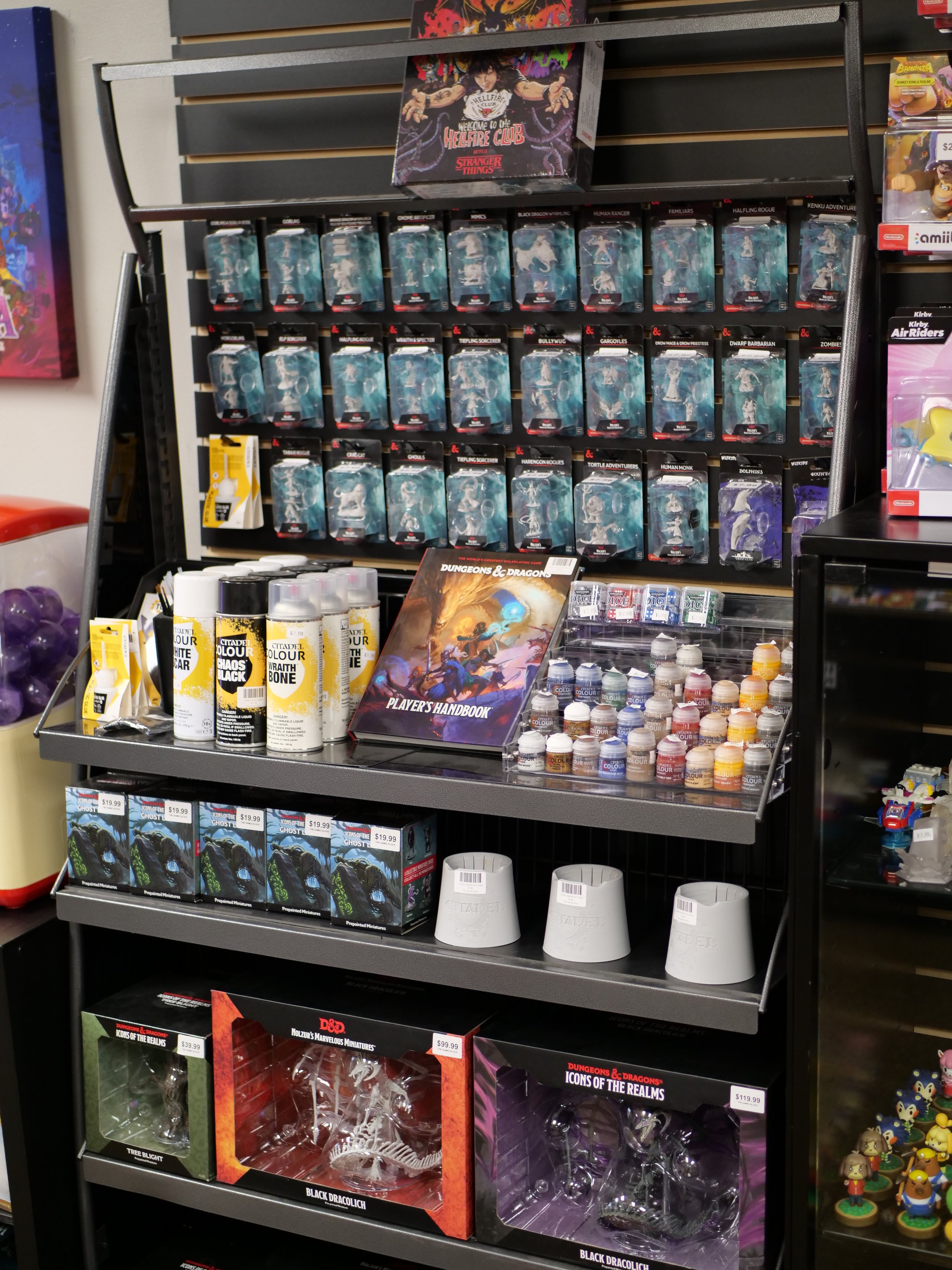 Display of Dungeons & Dragons miniatures, paints, and accessories in a store.