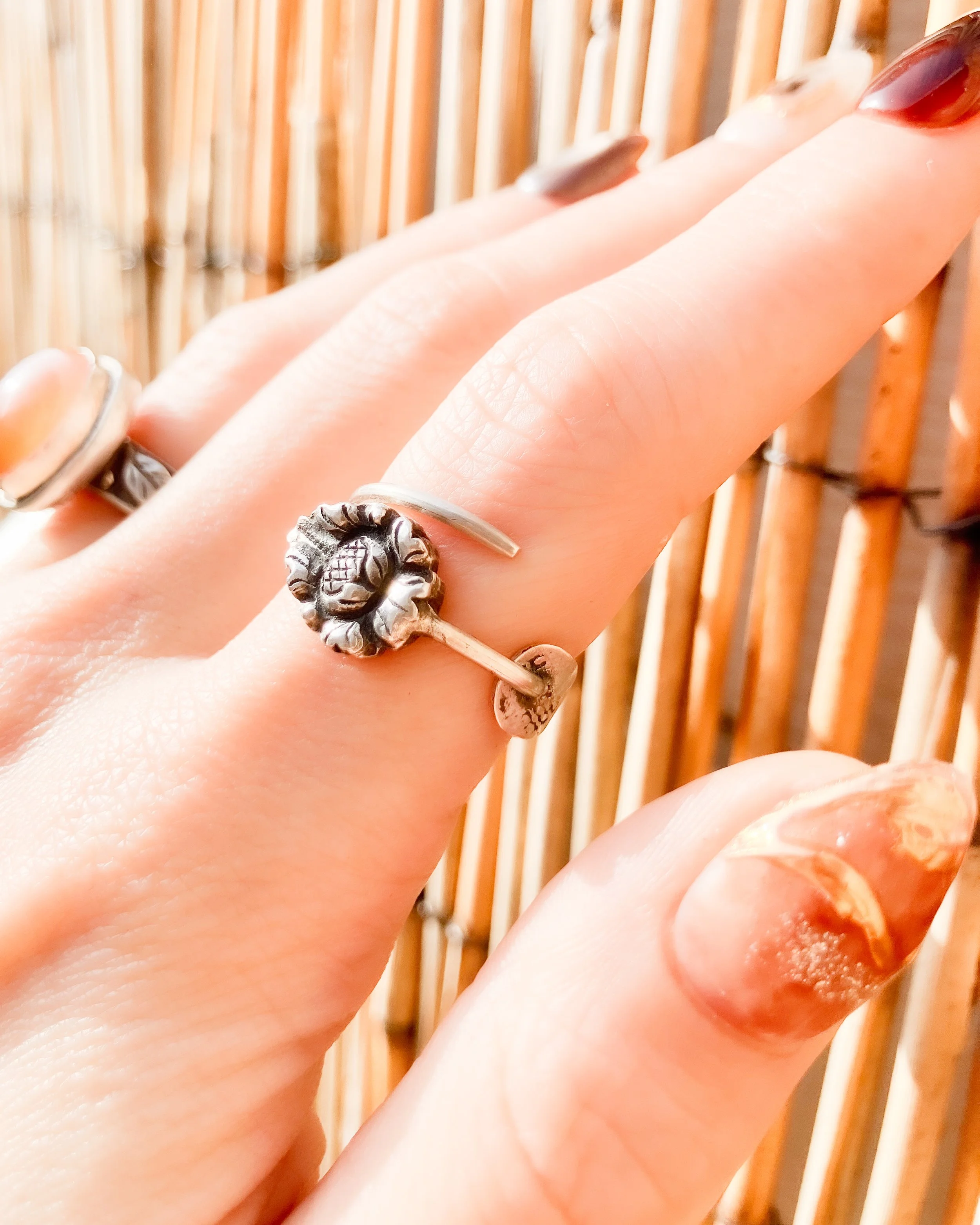 Vintage German 800 silver rings handmade in the Netherlands from cocktail picks, ornate Jugendstil flower motif, on human hand against rotan background