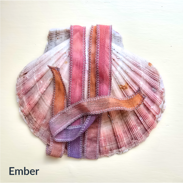 Upcycled Indian sari silk ribbon in coral, orange and warm pink, draped on a pink scallop shell