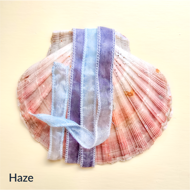 Upcycled Indian sari silk ribbon in lavender, blue and pearl, draped on a pink scallop shell