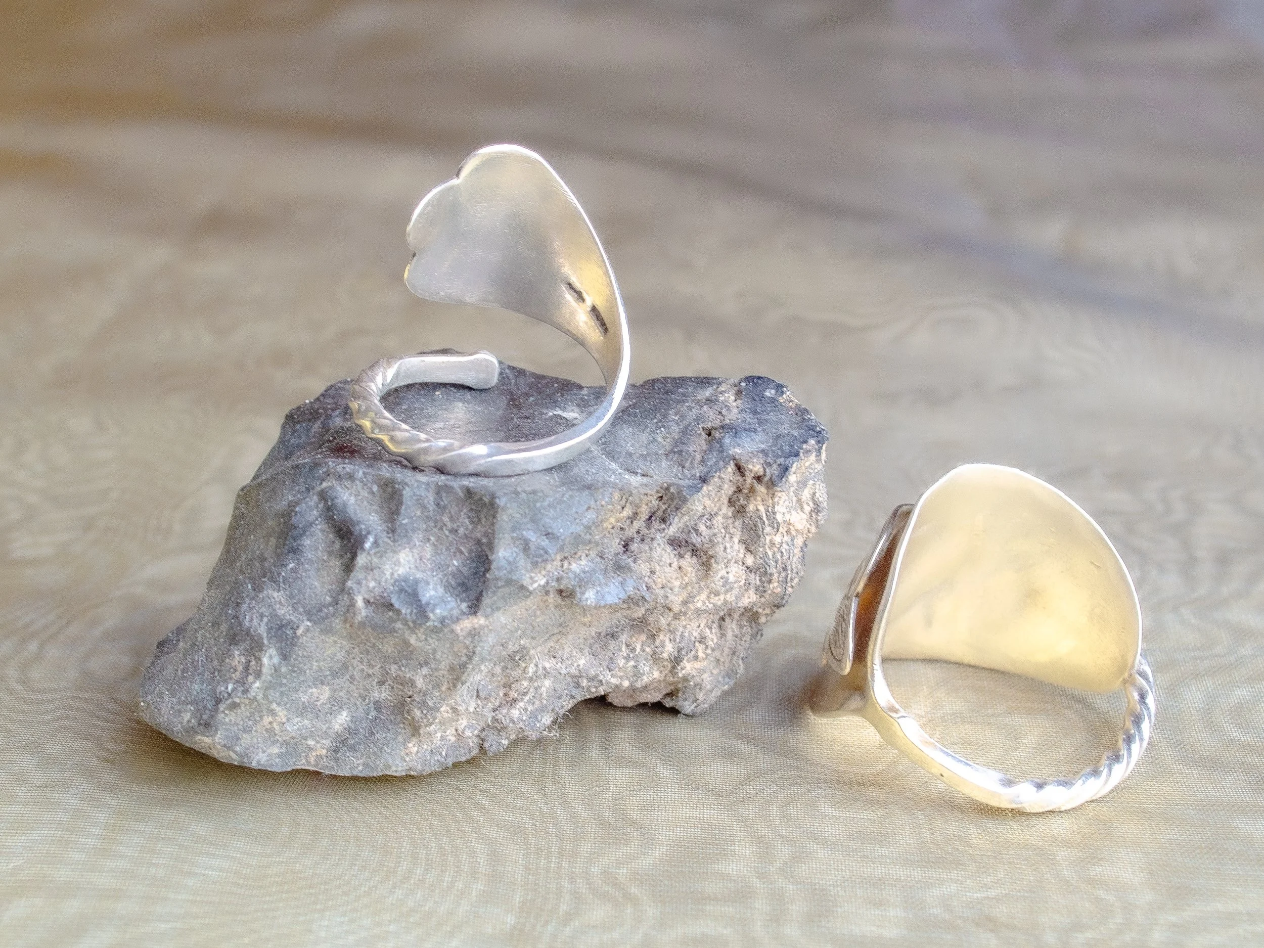 Two vintage Dutch 925 sterling silver heart spoon rings handmade by Moonlit Manor Netherlands, heart-shaped bowl motif with Art Nouveau engraving, on grey stone