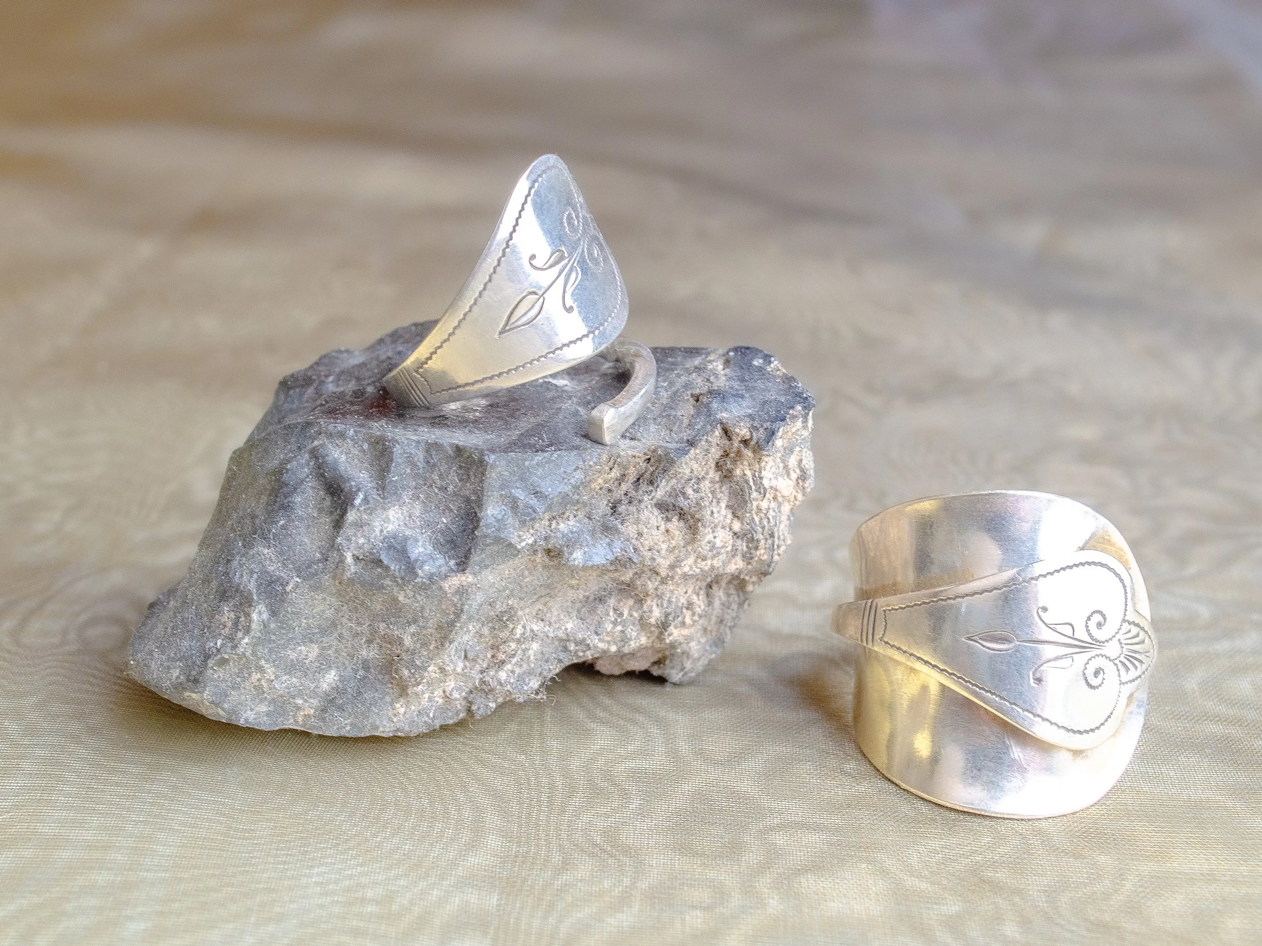 Two vintage Dutch 925 sterling silver heart spoon rings handmade by Moonlit Manor Netherlands, heart-shaped bowl motif with Art Nouveau engraving, on grey stone