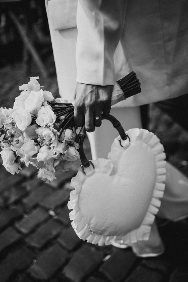 Eine Hand hält einen Blumenstrauß und eine Herzförmige Tasche, in schwarz-weiß