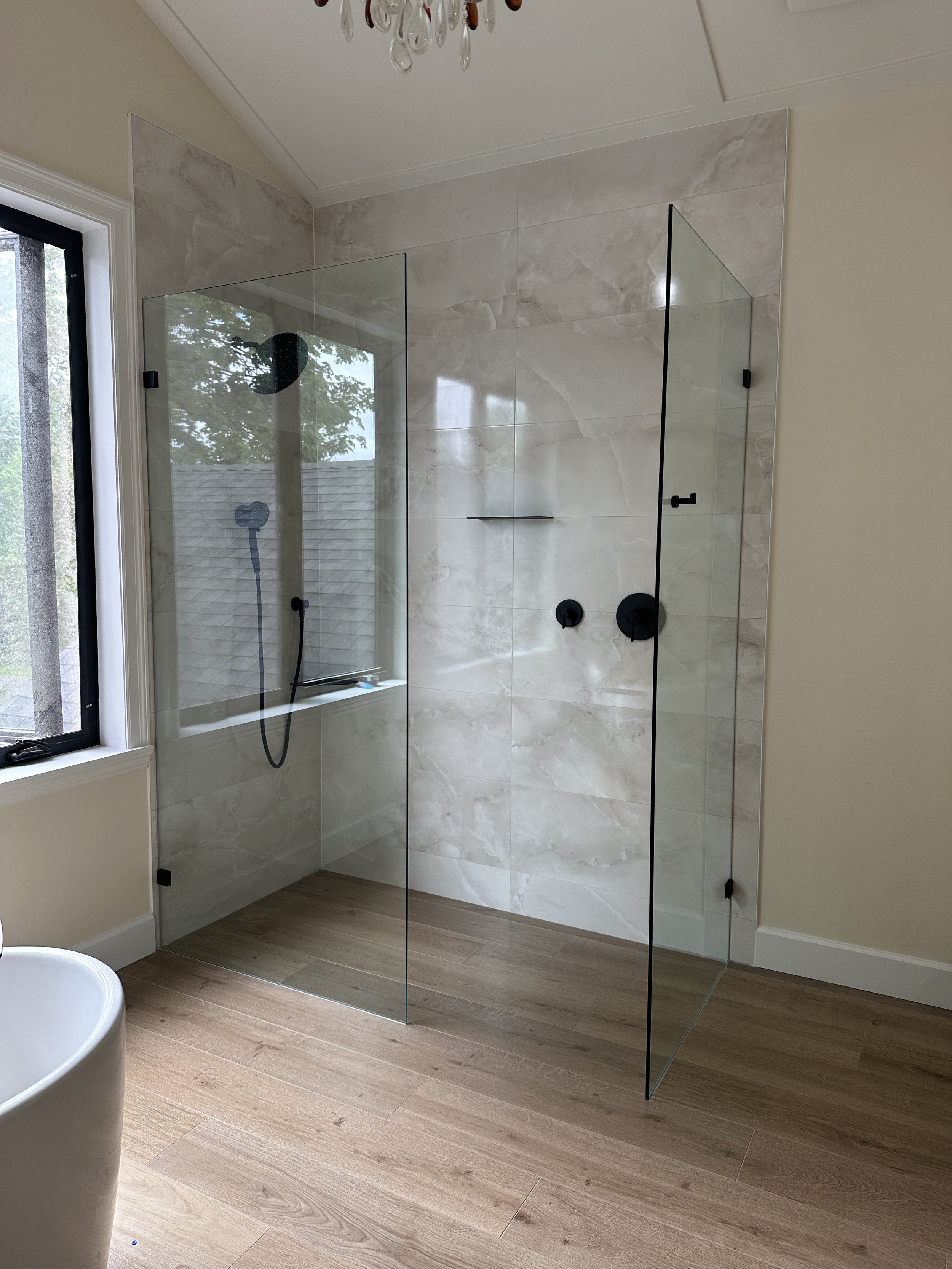 "A curbless glass walk-in shower with integrated bench seating, showcasing an Adaptiv Home aging-in-place renovation by M1 Custom Bathrooms."