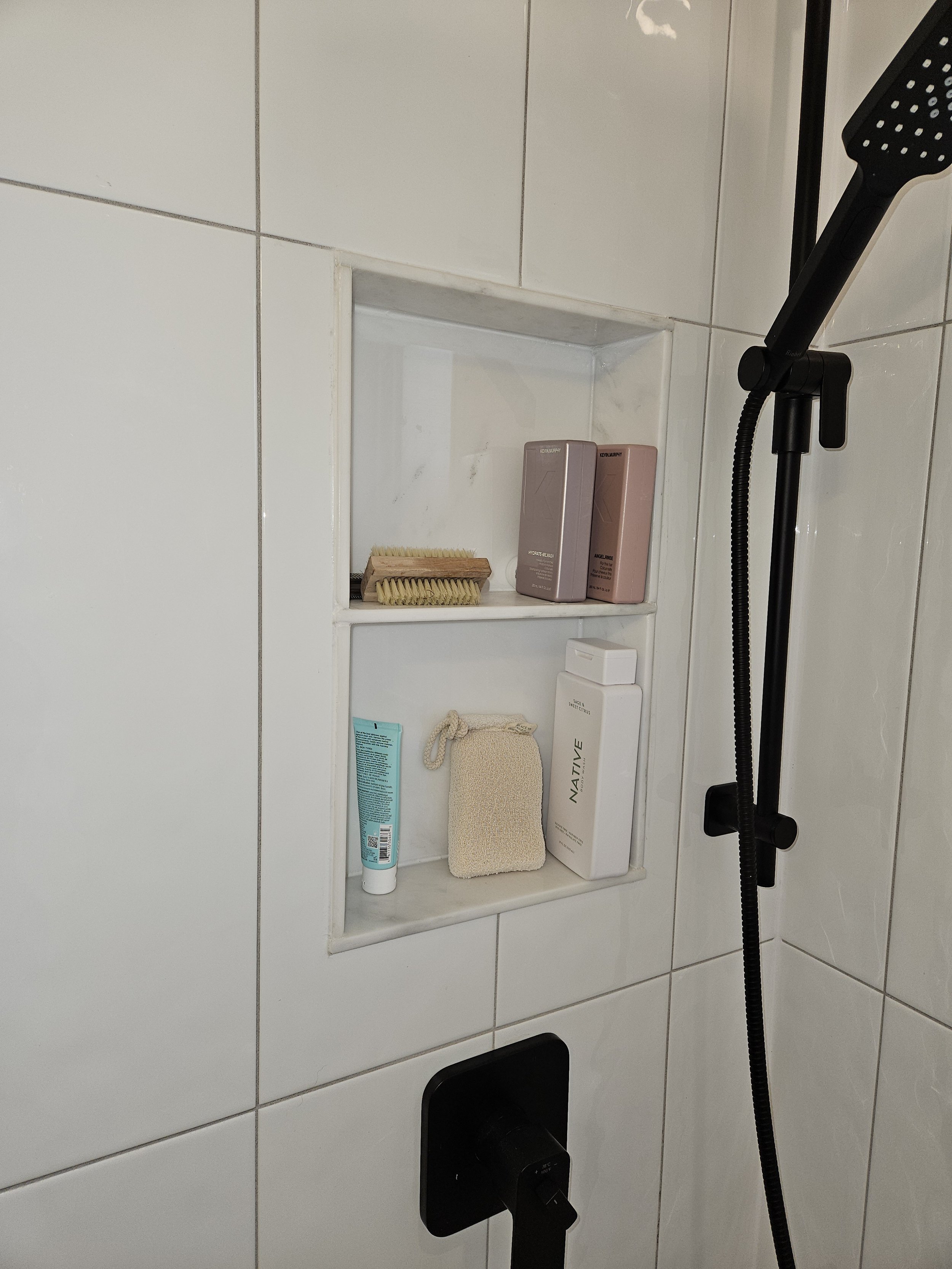 "Close-up of a high-end shower niche with premium finishes and modern hardware, showcasing the Signature bathroom remodel package available in the Fraser Valley."