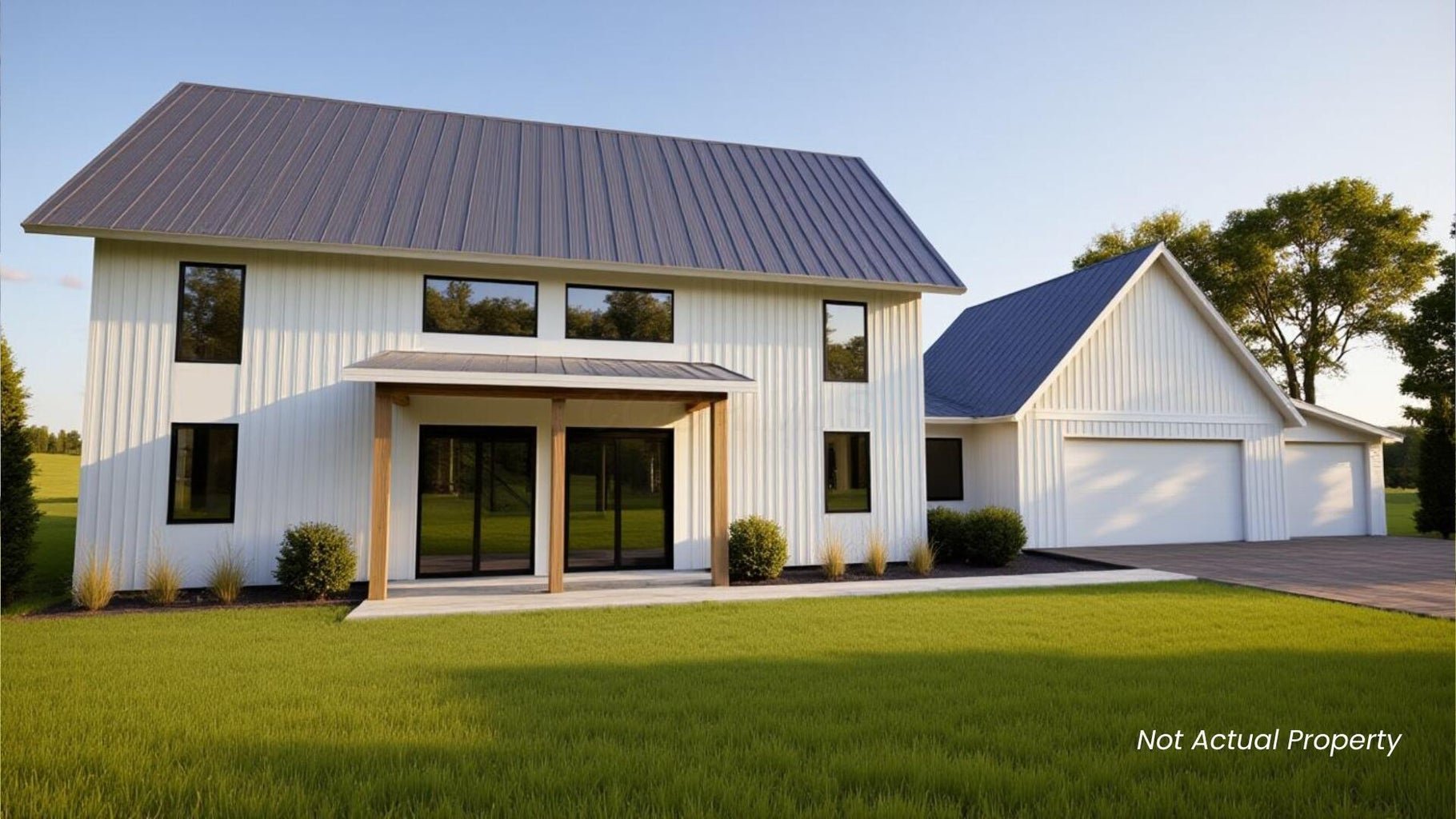 Modern white two-story house with a gray metal roof, large windows, and a two-car garage on a green lawn with trees in the background.